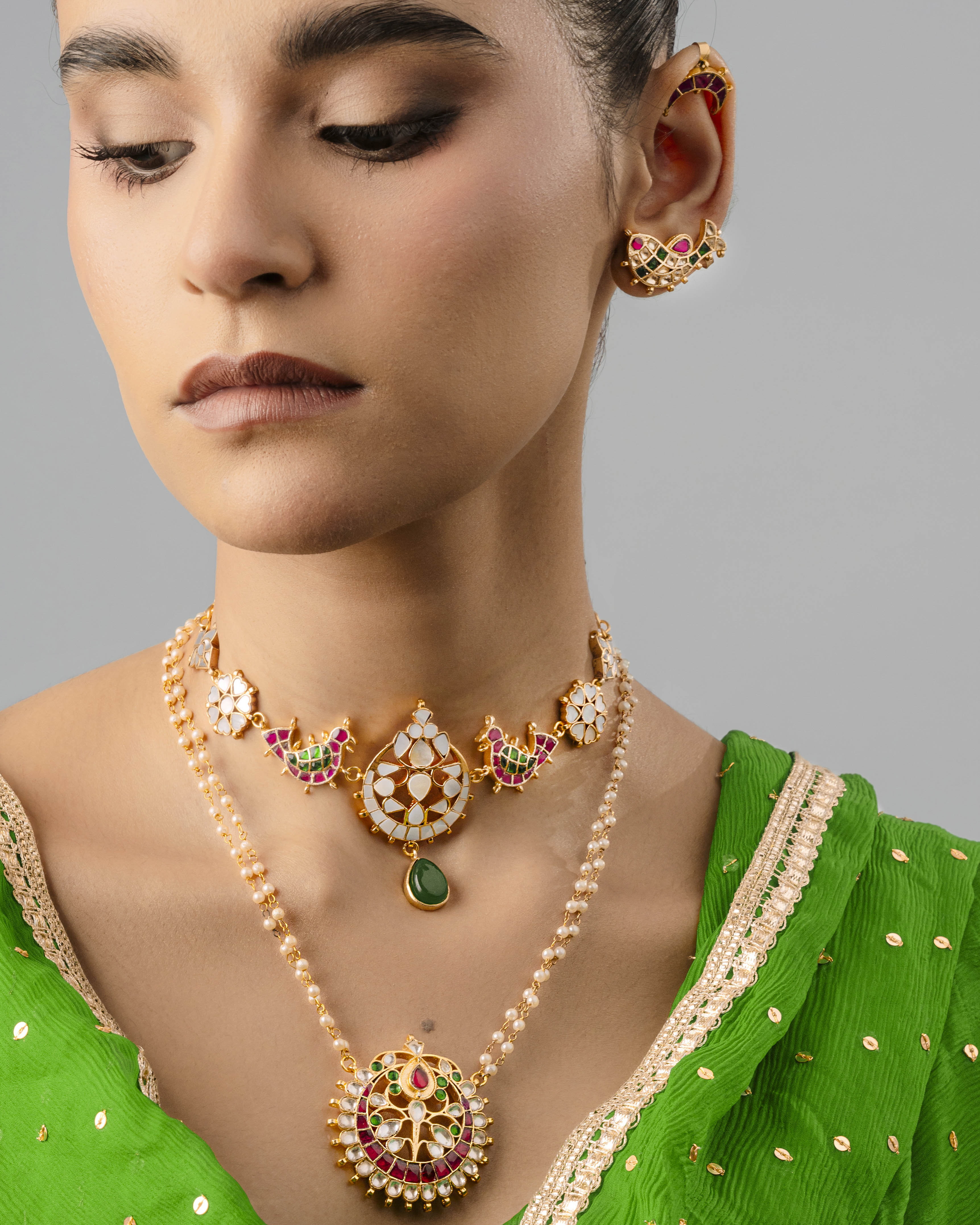 Exquisite handmade fish earring cuff displaying fine texture and craftsmanship, worn alongside a pearl-stringed choker.
