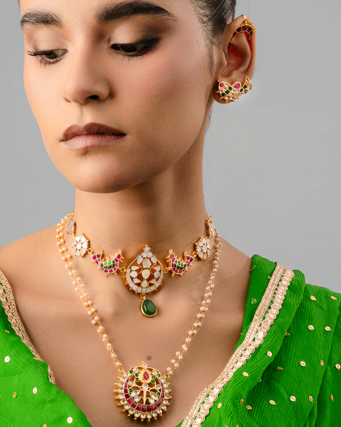 Exquisite handmade fish earring cuff displaying fine texture and craftsmanship, worn alongside a pearl-stringed choker.
