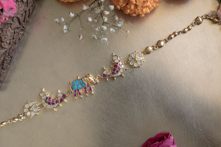 Handmade Aadhya gold-plated elephant enamel and polki necklace styled in an antique metal bowl for wedding jewelry showcase.
