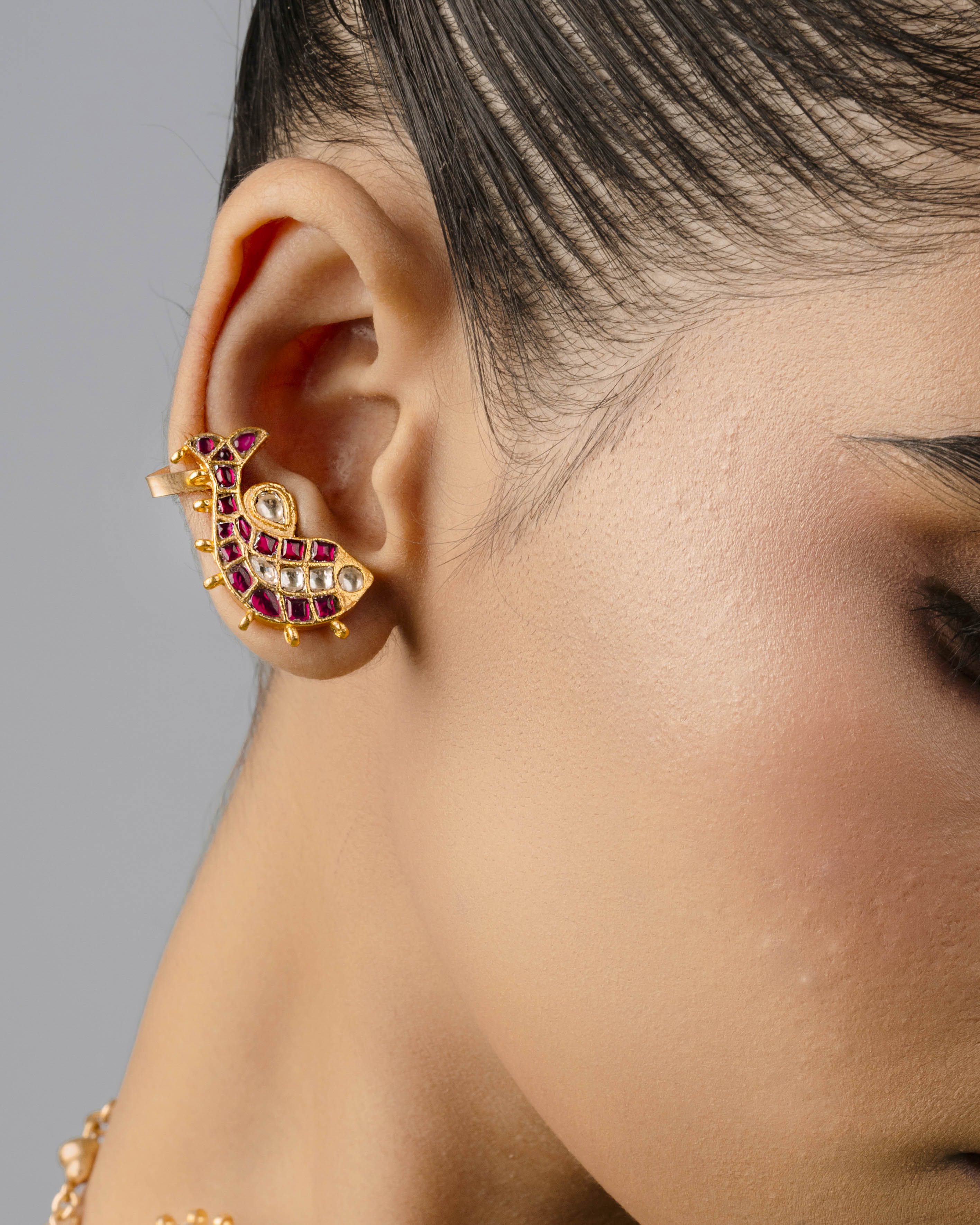 an adjustable 18k gold-plated fish-shaped ear cuff symbolizing prosperity, paired with festive Indian attire.