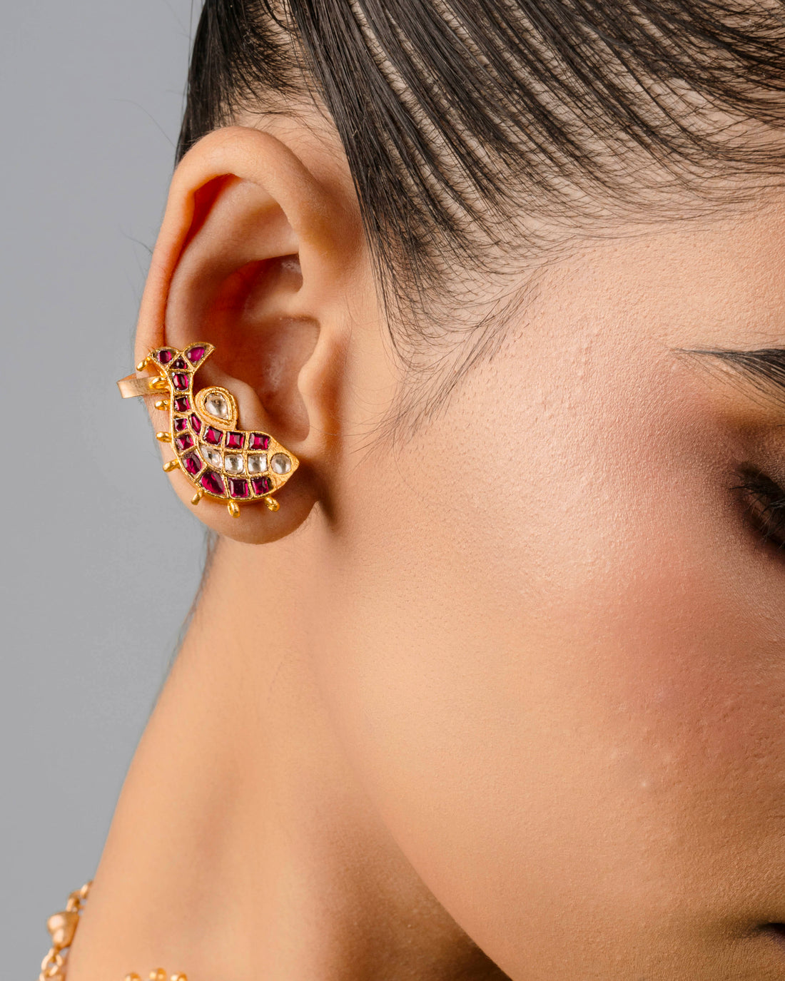an adjustable 18k gold-plated fish-shaped ear cuff symbolizing prosperity, paired with festive Indian attire.