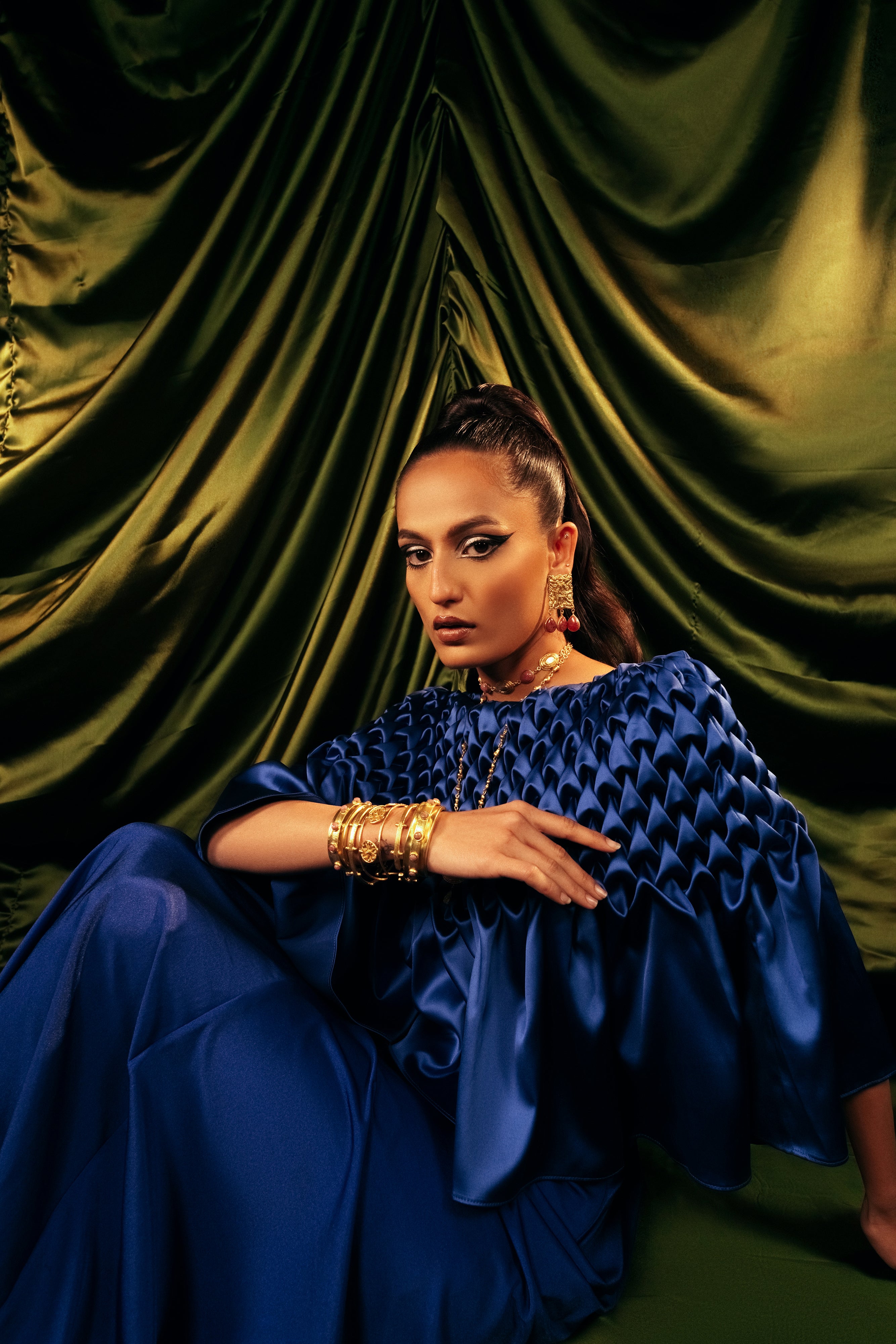Stackable set of 5 handcrafted openable gold bangles styled on a model in a blue outfit.