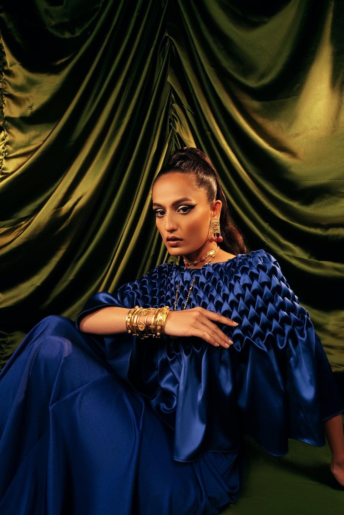 Stackable set of 5 handcrafted openable gold bangles styled on a model in a blue outfit.