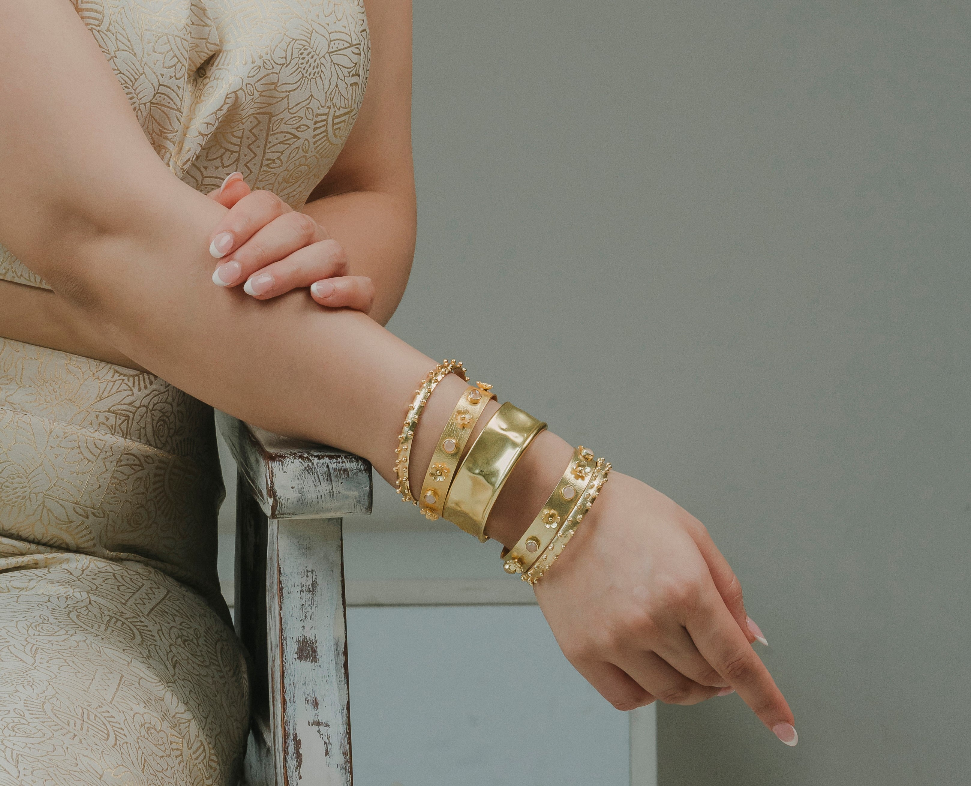A model demonstrating how to style a set of four chunky gold arm cuff bracelets for special occasions.