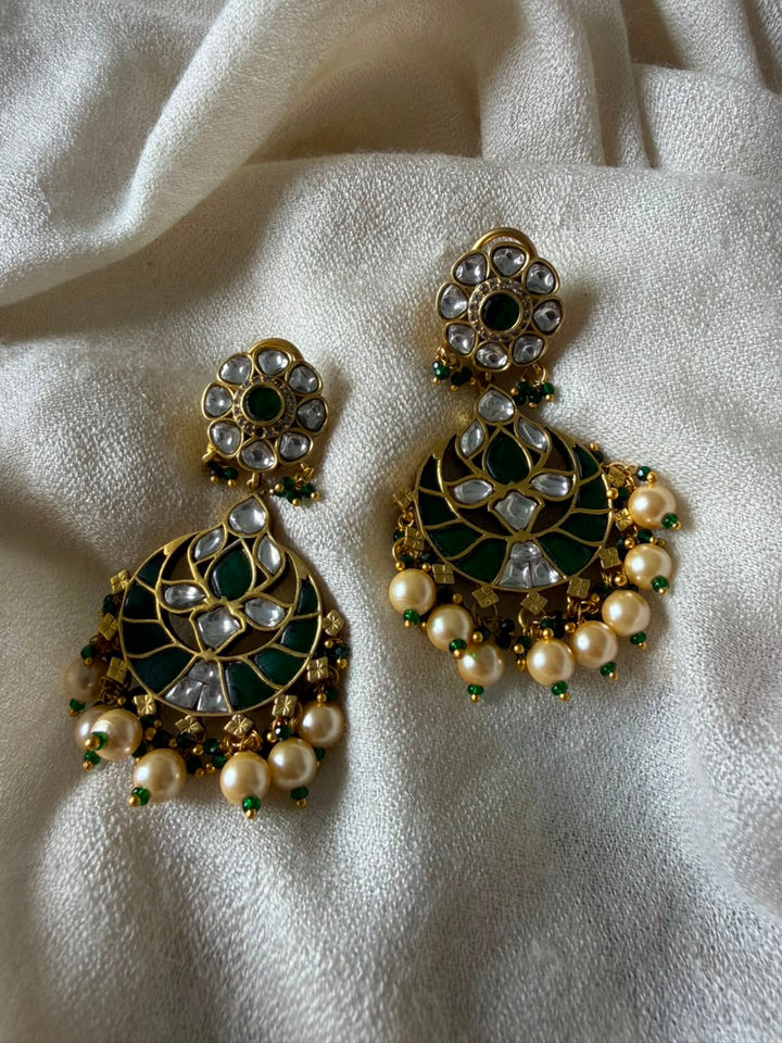 Pair of crescent-shaped green enamel Chandbali earrings detailed with Kundan stones and pearl cluster drops.