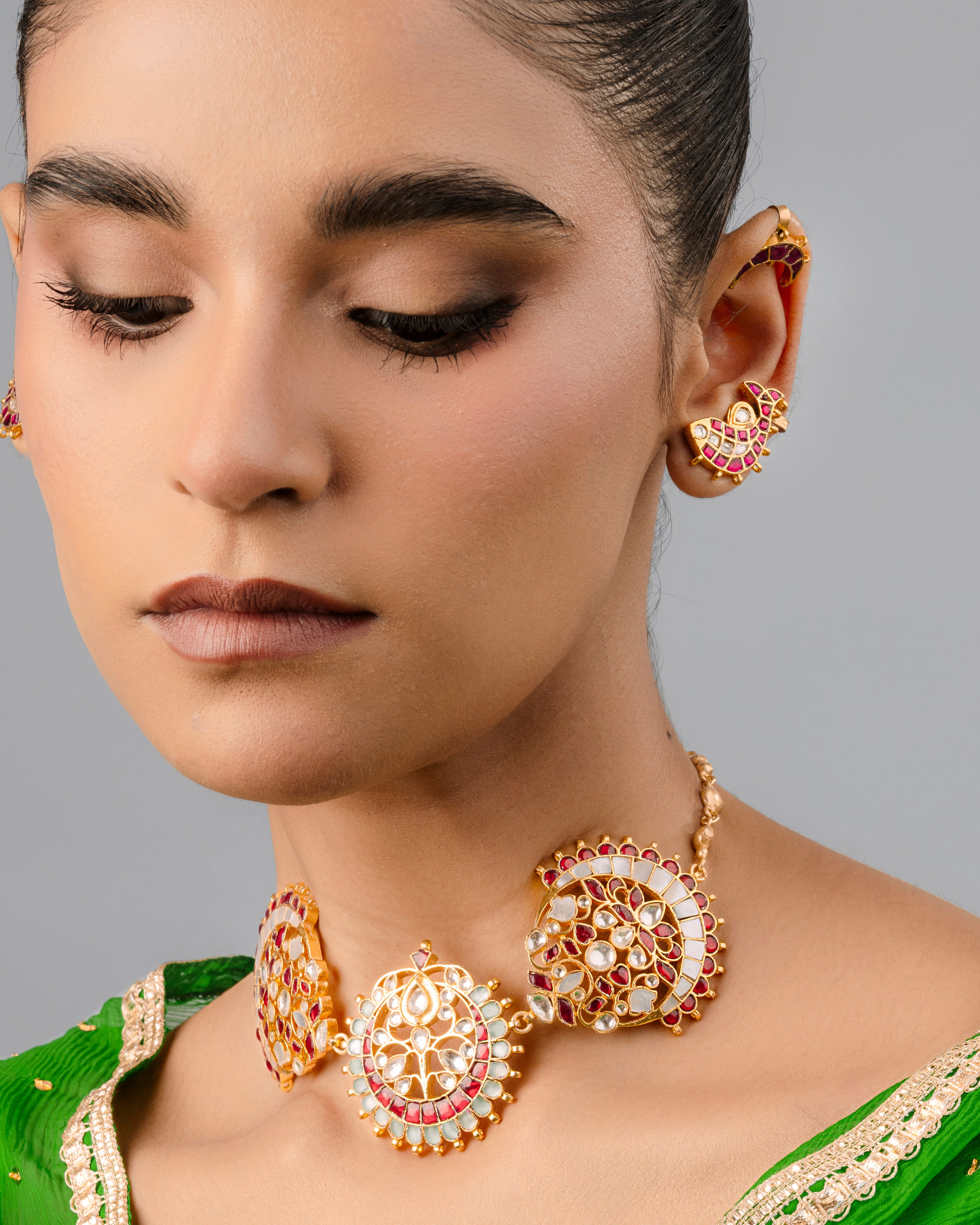 An elegantly designed Indian bridal Kundan choker necklace featuring twin crescent moon-shaped side panels and a central round floral medallion, detailed with red gemstones and a hanging white pearl trim.
