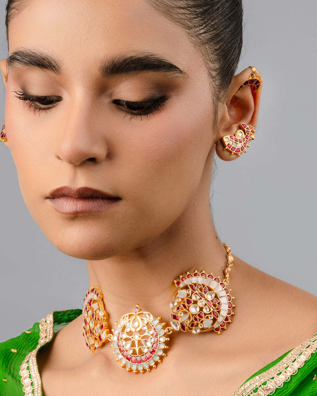 An elegantly designed Indian bridal Kundan choker necklace featuring twin crescent moon-shaped side panels and a central round floral medallion, detailed with red gemstones and a hanging white pearl trim.