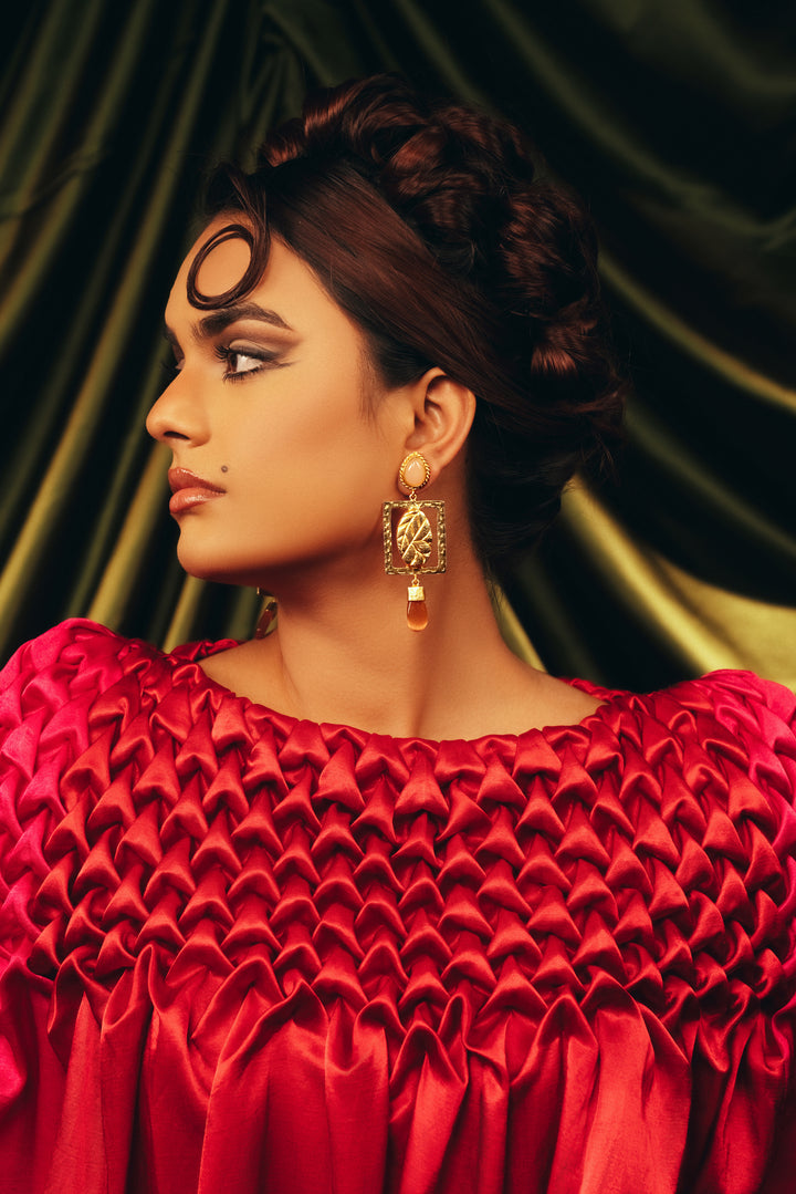 18k gold-plated leaf dangle earrings with ruby zoisite stones and a red textured dress.
