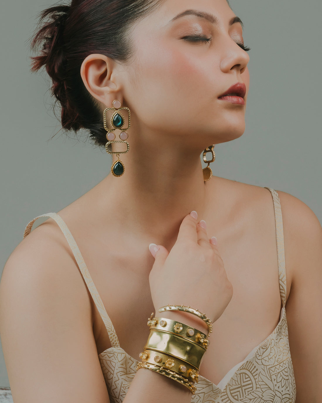 Model styled in a set of four stackable gold kadas featuring floral embellishments and rose quartz details.