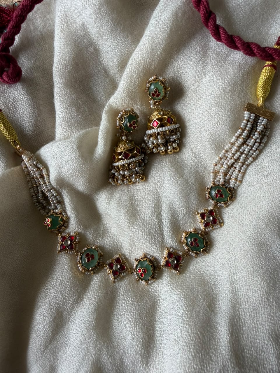 Traditional Indian wedding jewelry set featuring a multi-strand pearl choker necklace with square Kundan accents and heavy gold-plated Jhumkas.