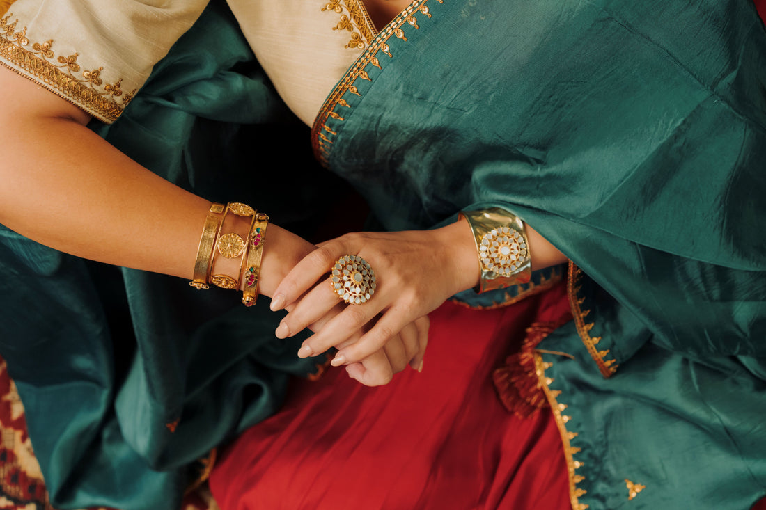 Ornate flower-shaped gold ring with white iridescent mother of pearl gemstone petals displayed outdoors.