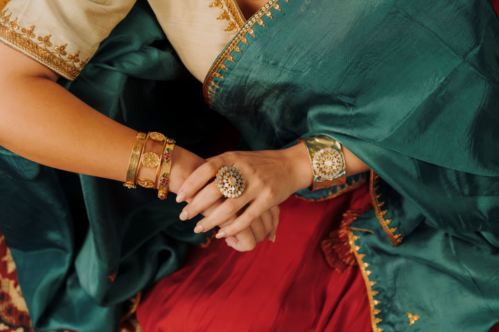 Ornate flower-shaped gold ring with white iridescent mother of pearl gemstone petals displayed outdoors.