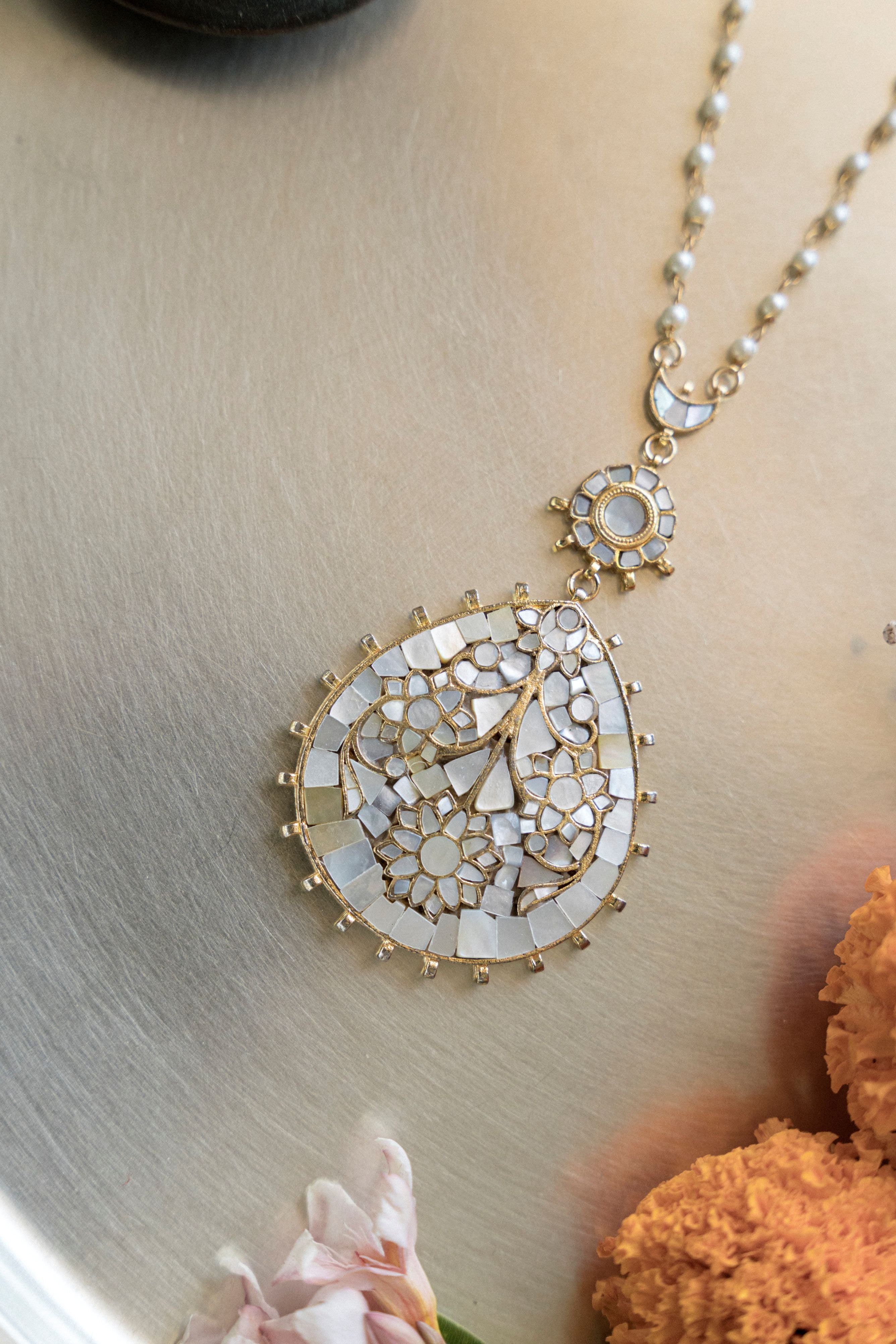Model wearing handcrafted mother of pearl teardrop pendant necklace and layered chandelier earrings for festive look