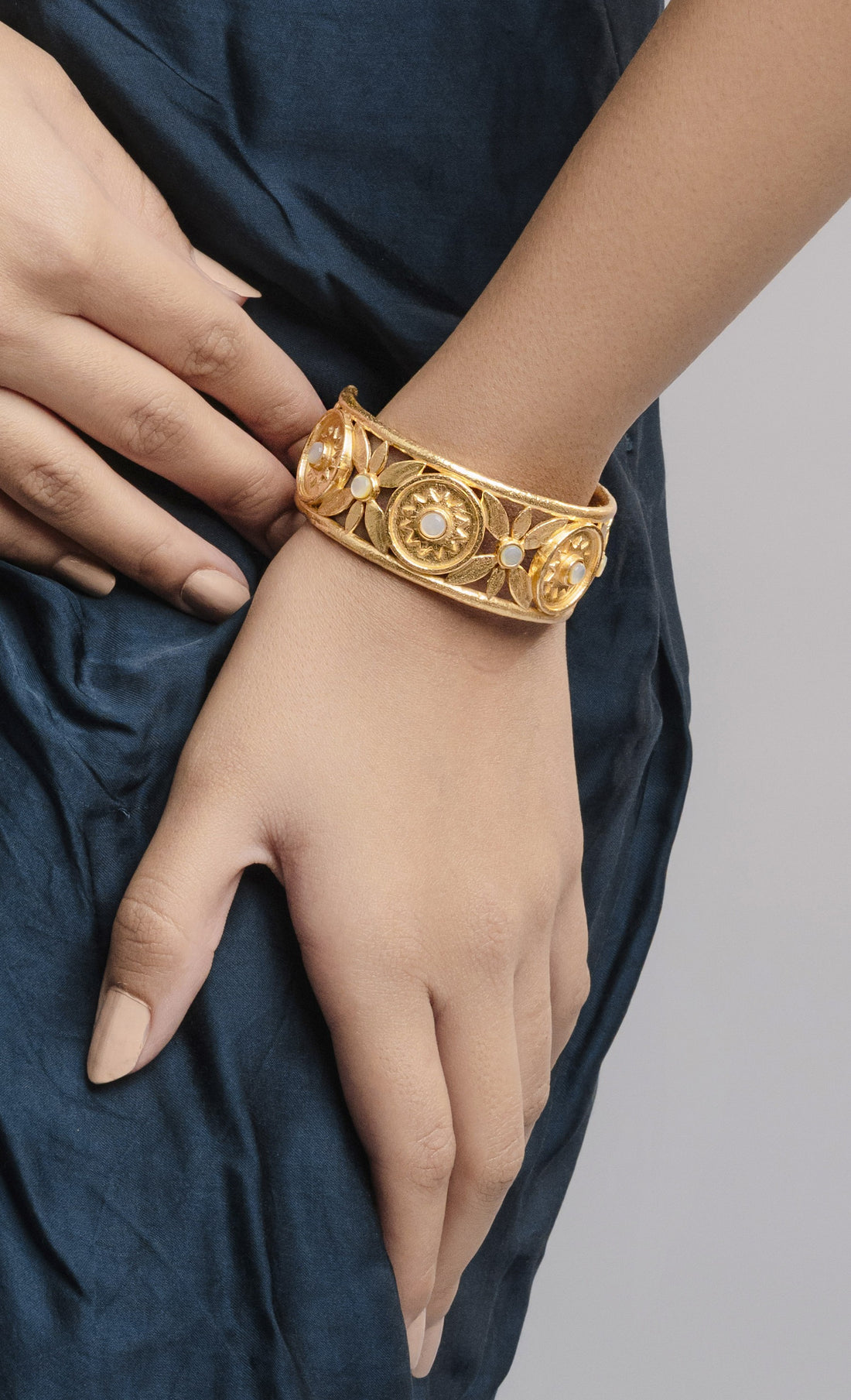 A bold, handcrafted brass alloy women's kada with an antique 18k gold-plated finish, showcasing detailed floral engravings and mother-of-pearl embellishments.