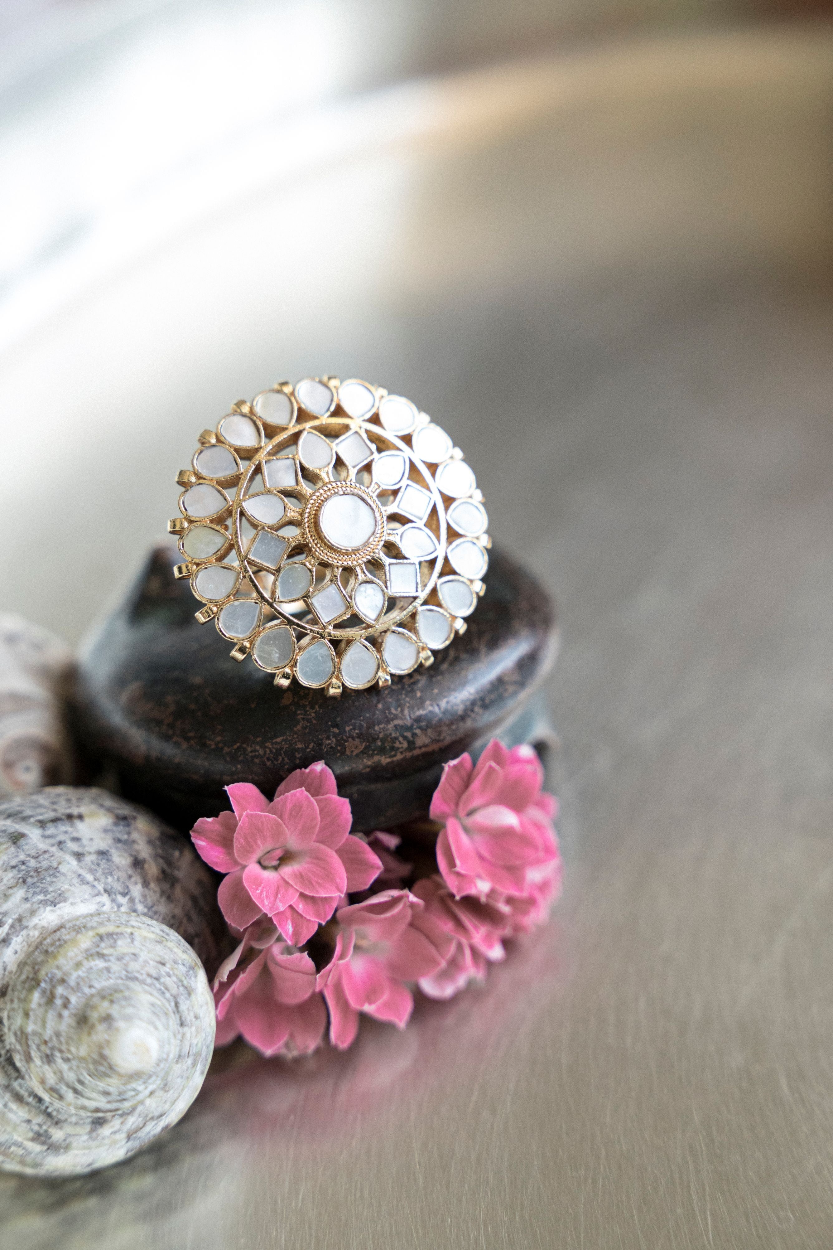 Gold-plated statement ring featuring an intricate floral motif inlaid with mother of pearl stones.