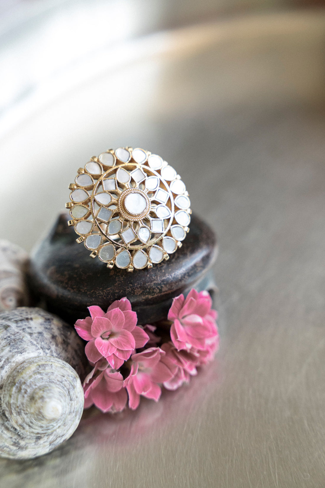 Gold-plated statement ring featuring an intricate floral motif inlaid with mother of pearl stones.