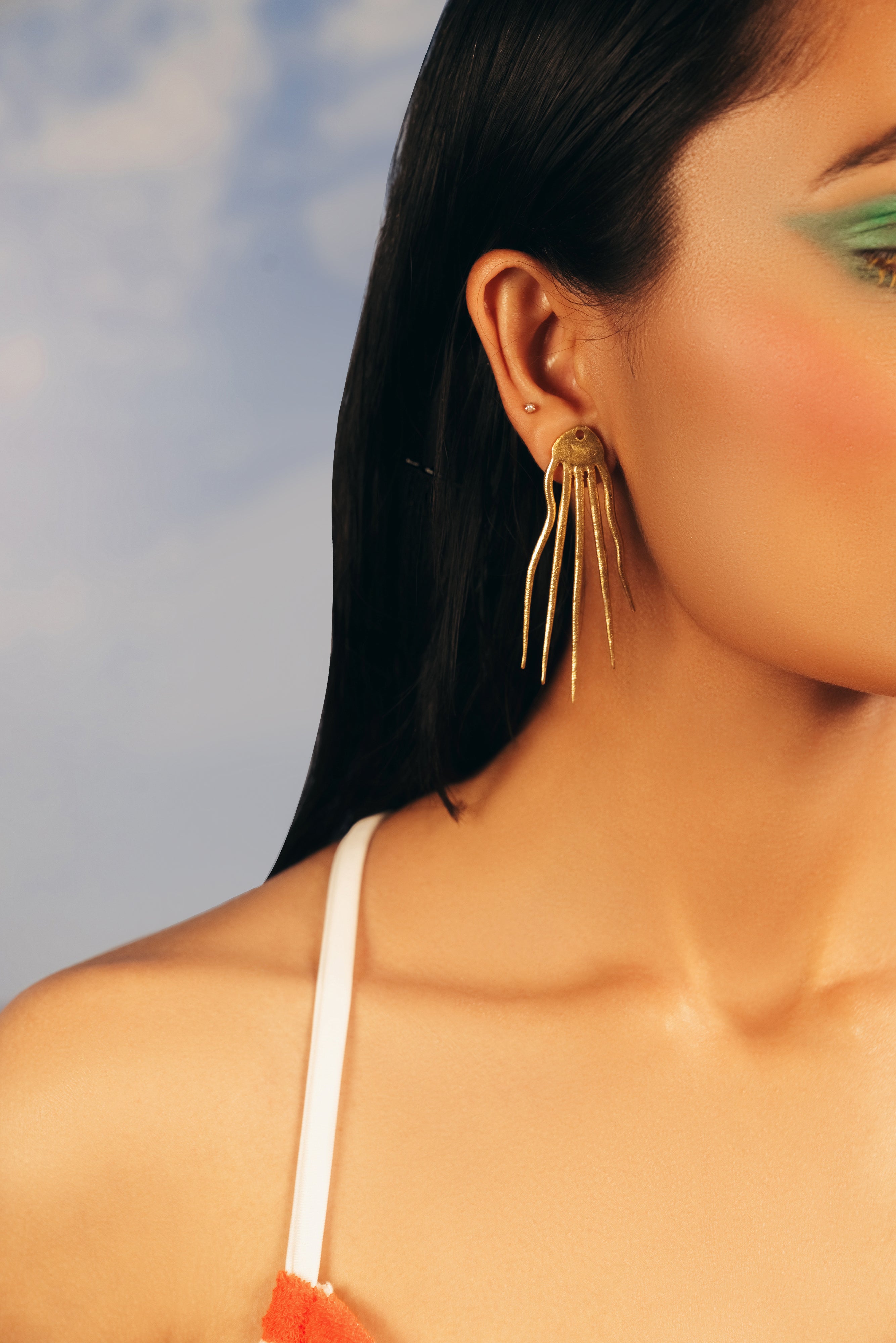 Model wearing gold Octo resort earrings paired with an off-shoulder black sweater.