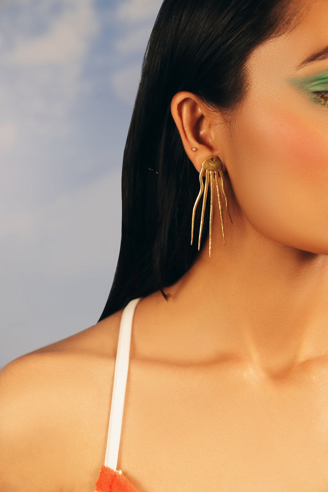 Model wearing gold Octo resort earrings paired with an off-shoulder black sweater.