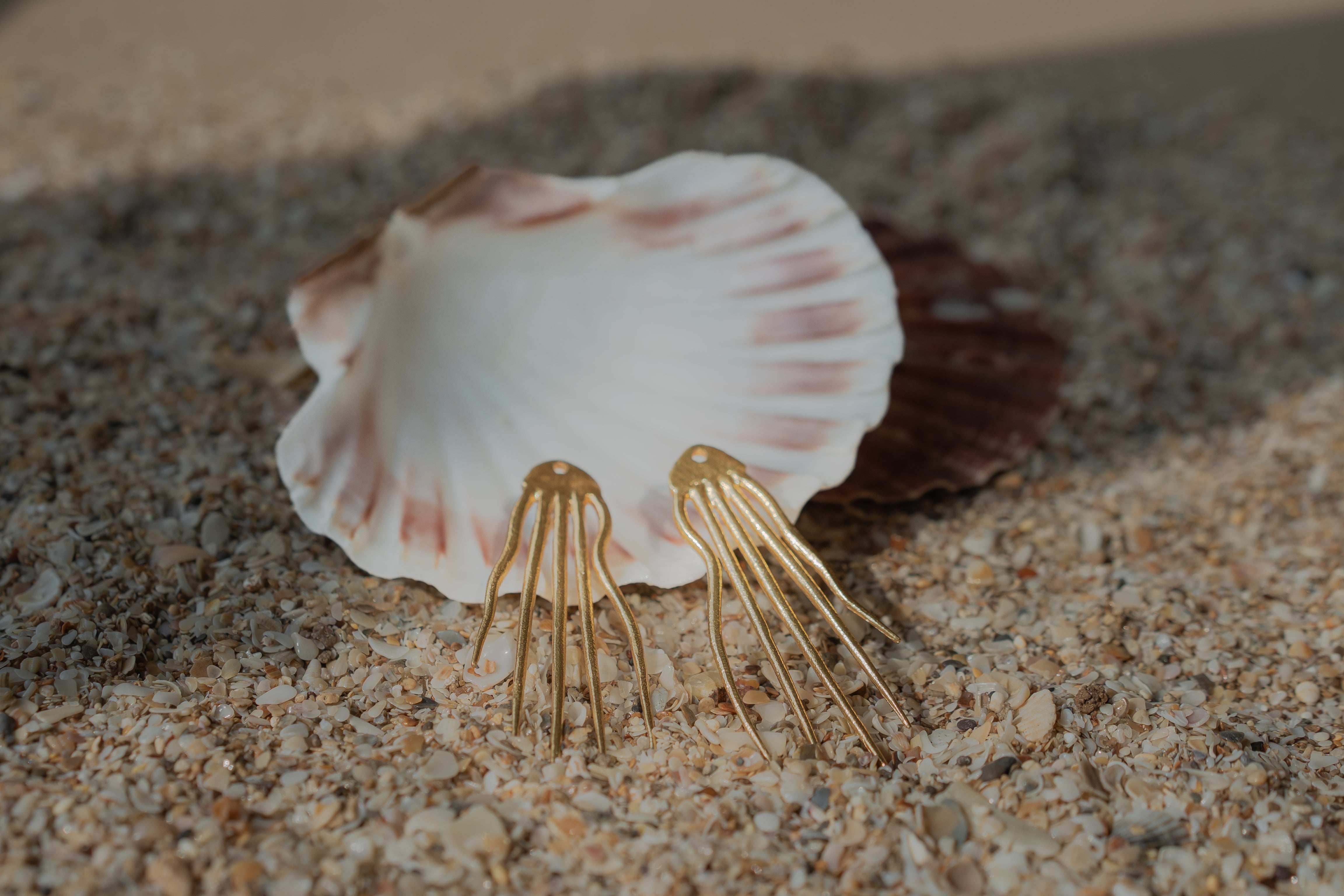 Gold-plated Octo wave drop earrings styled on a model wearing an off-shoulder outfit.