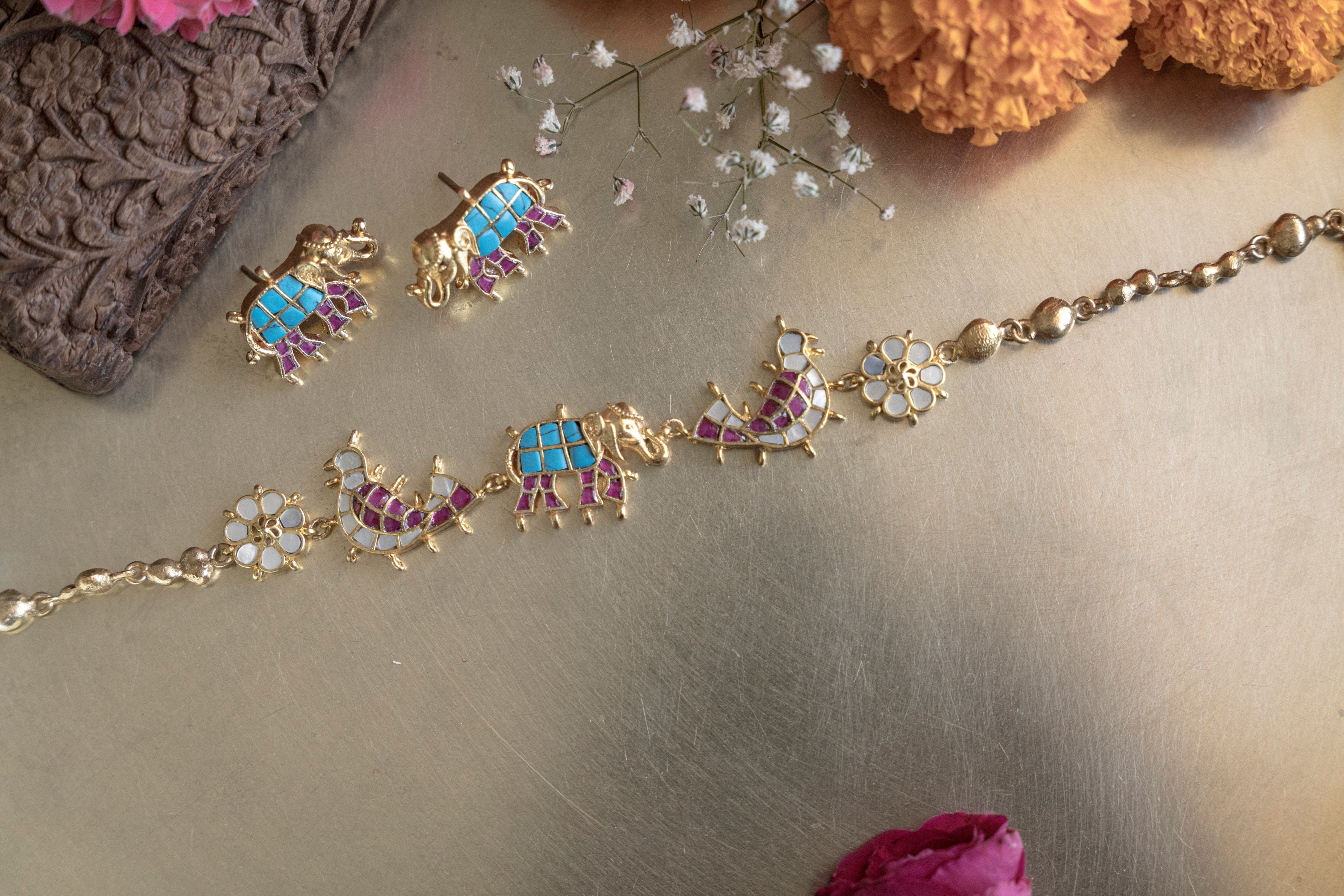 Handcrafted royal elephant meenakari polki choker necklace with turquoise and pink enamel details surrounded by festive flowers.