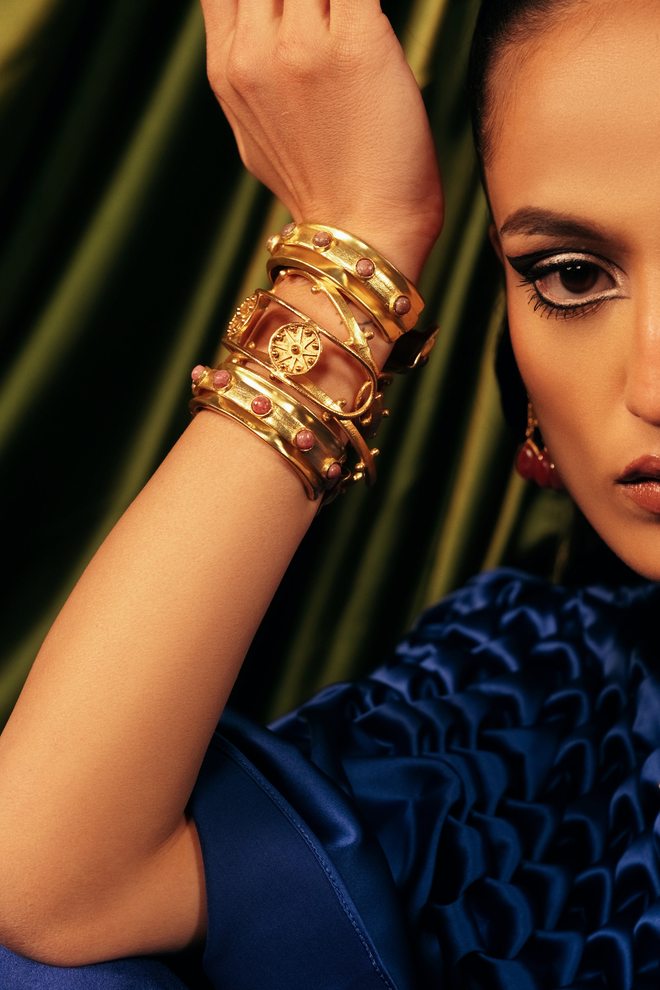 Woman wearing statement hand-crafted gold kadas with pink stones and raised stud detailing.