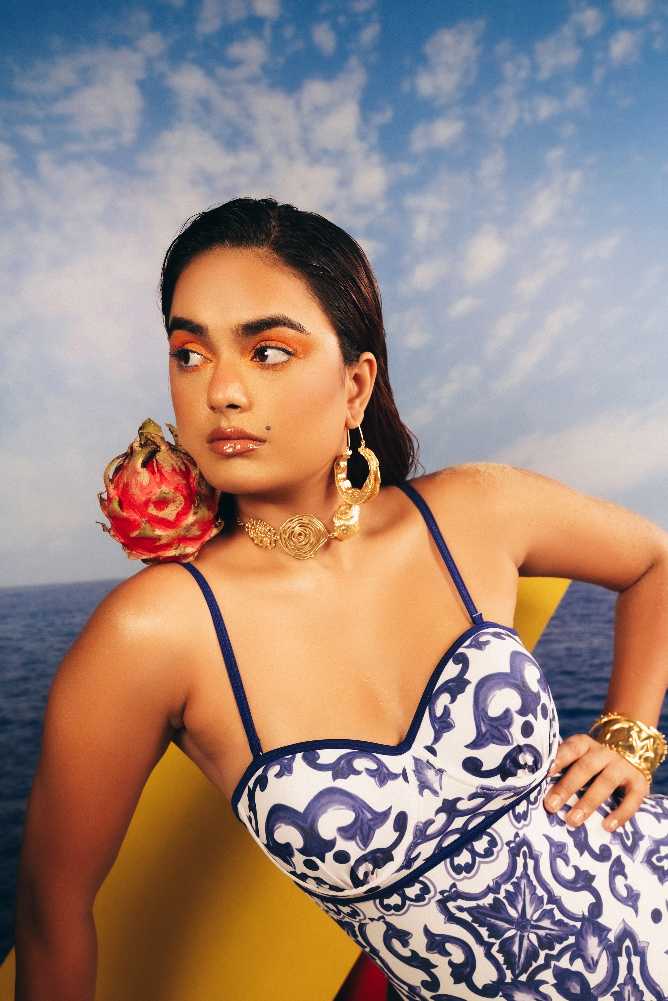 Model styled in a blue patterned top wearing a statement gold floral choker necklace.