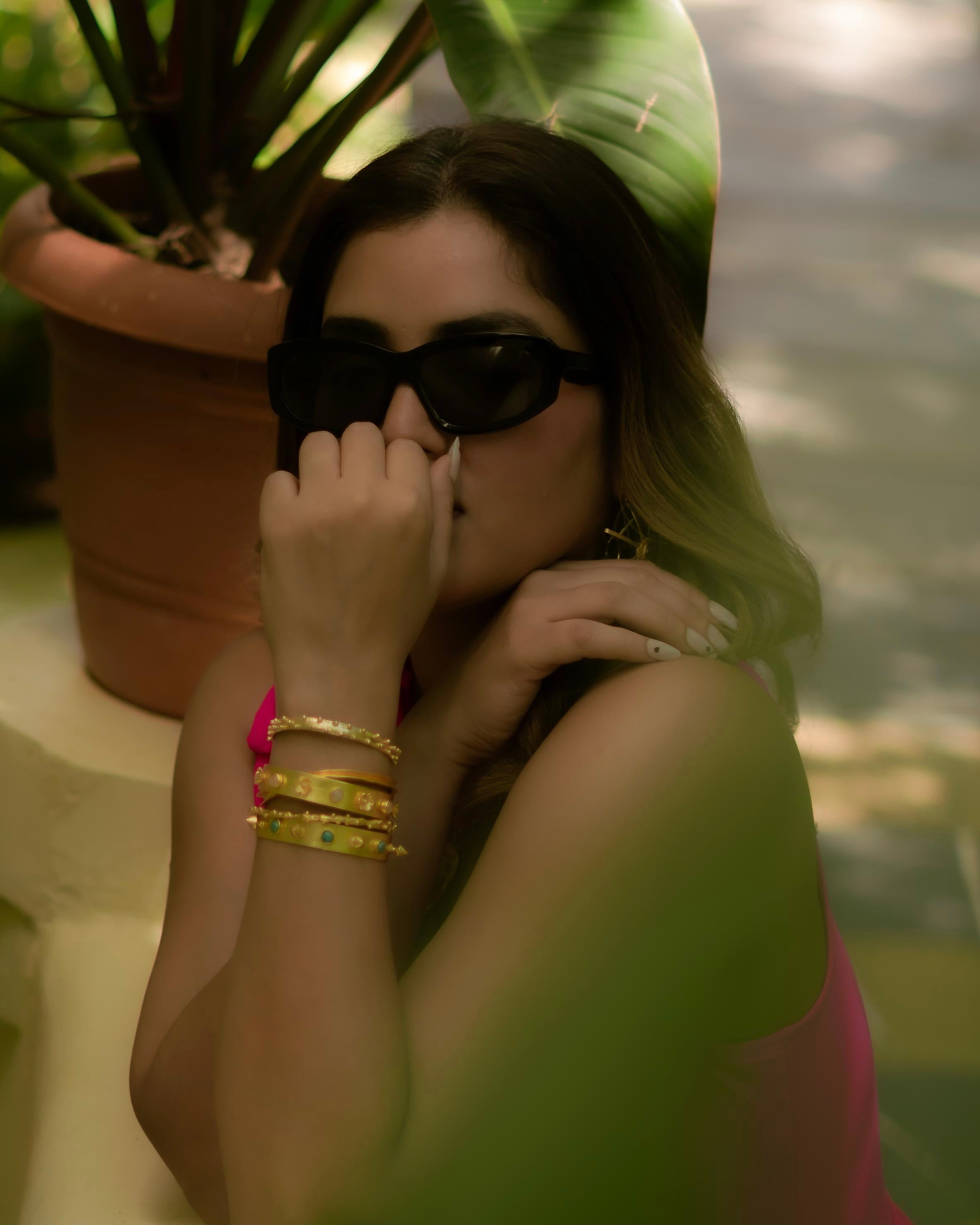 Model wearing 18k gold plated stacked kadas with turquoise stone details on wrist