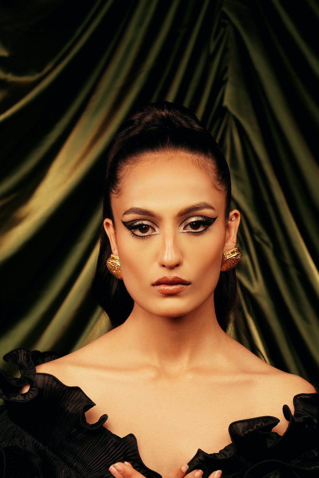 Woman wearing large round gold-colored Sunlit Sphere stud earrings paired with a black dress.