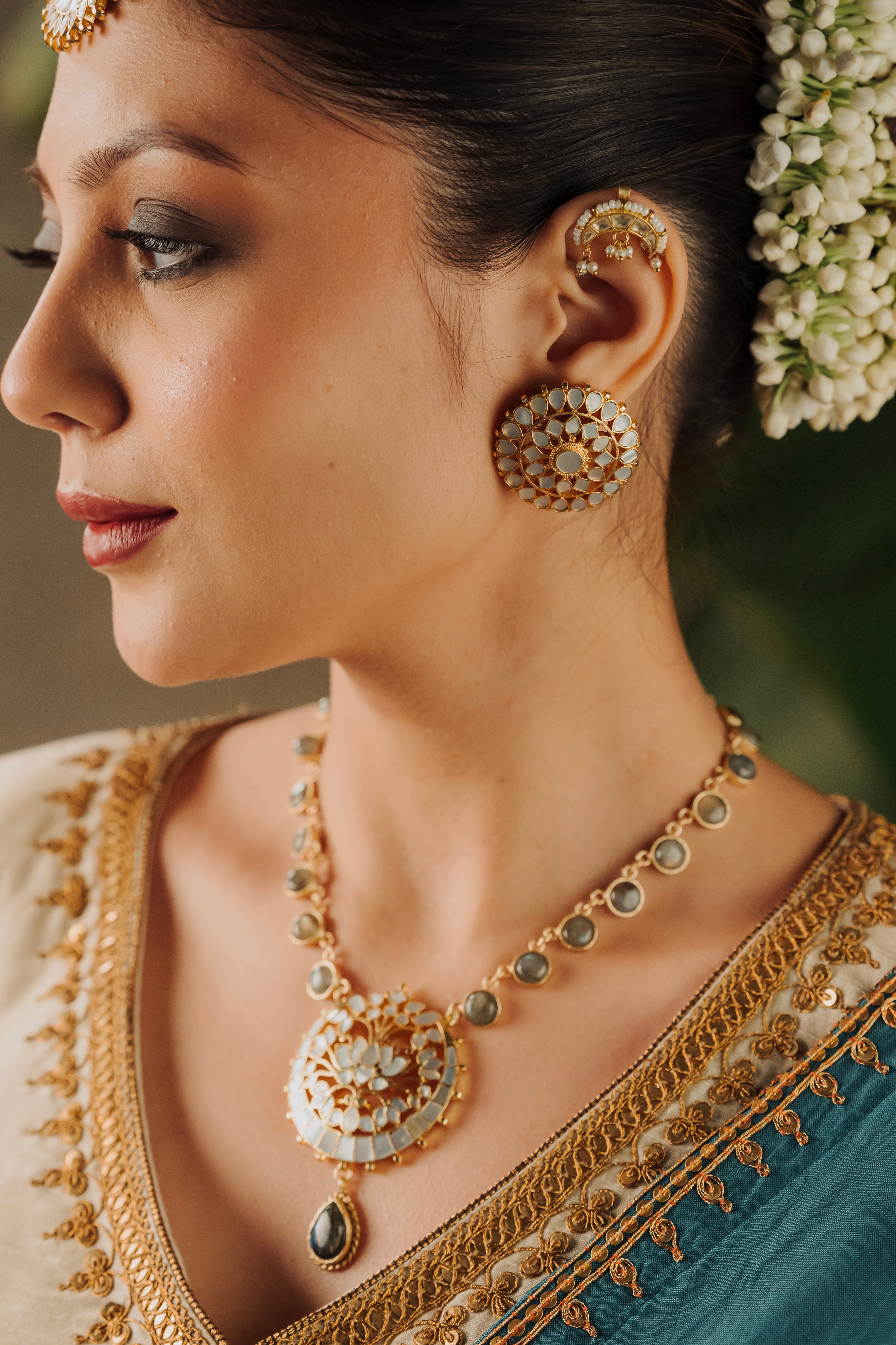 Indian bride wearing a traditional temple necklace featuring a circular lotus pendant and teardrop stone dangler.