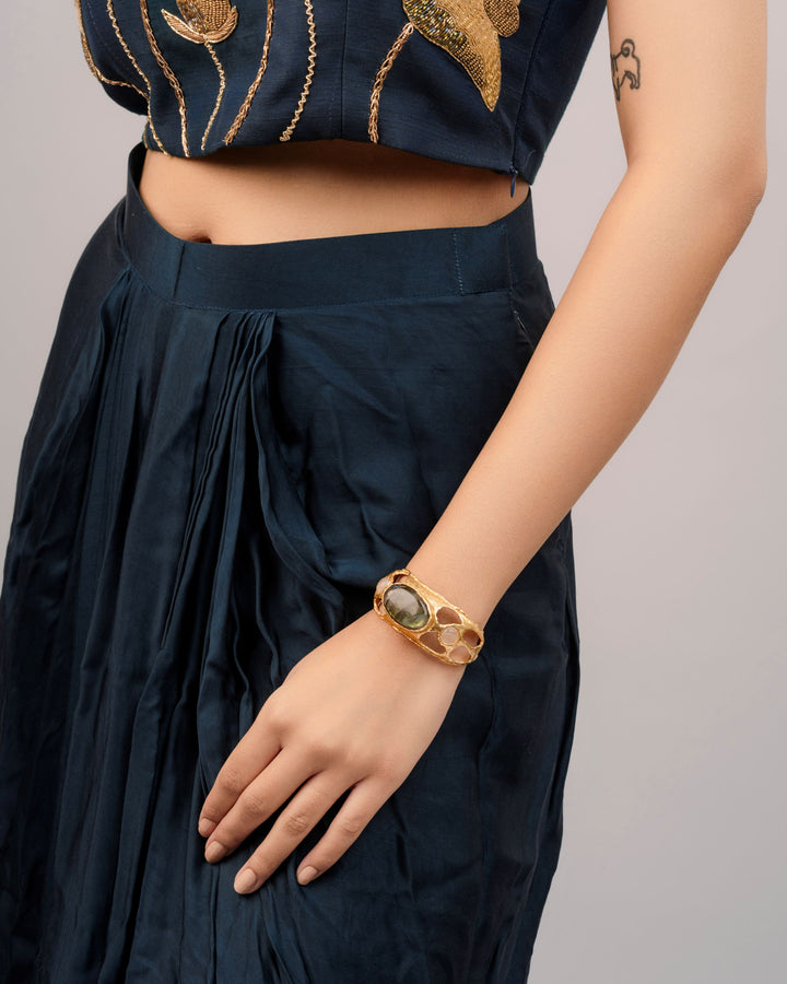 Ethically handmade brass alloy cuff bracelet with skin-friendly gold plating and a polished green gemstone.