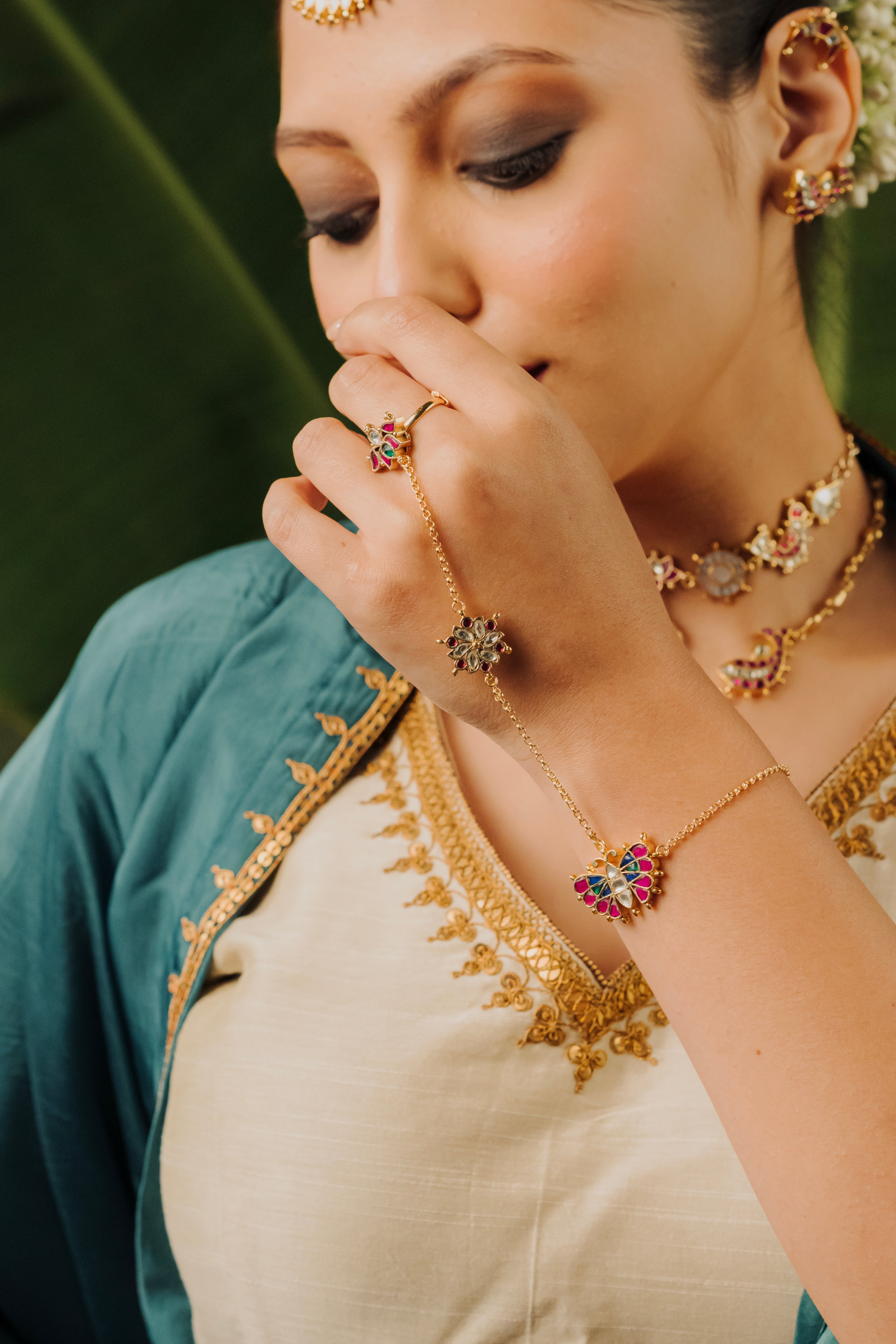 Woman wearing gold-plated Titli butterfly hathphool bracelet with colorful stones.