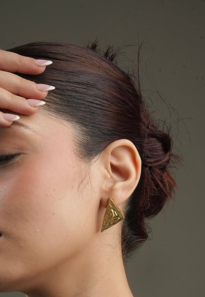 woman wearing gold-toned geometric triangular statement drop earrings made of allergy-free brass.