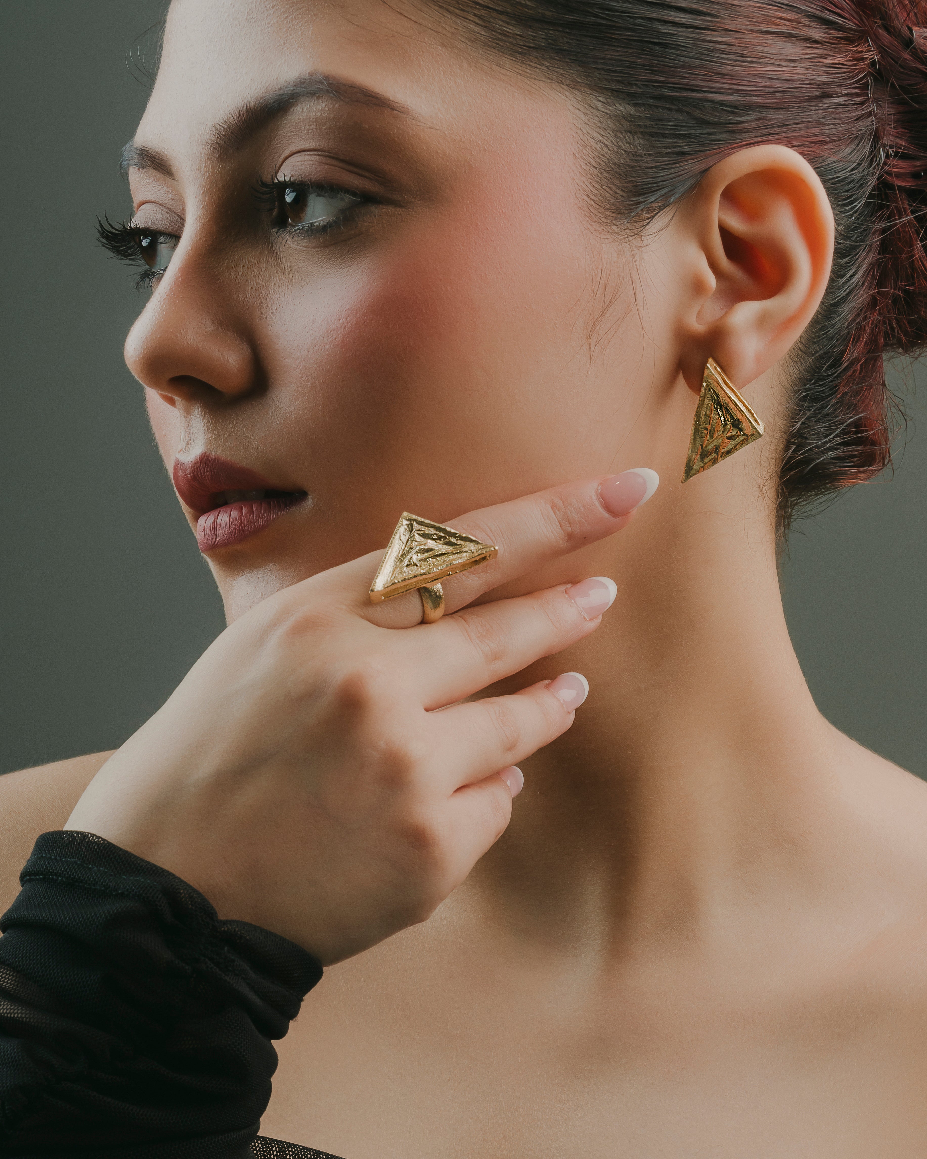 Modern geometric gold statement earring crafted from allergy-free brass shown on a model's ear.
