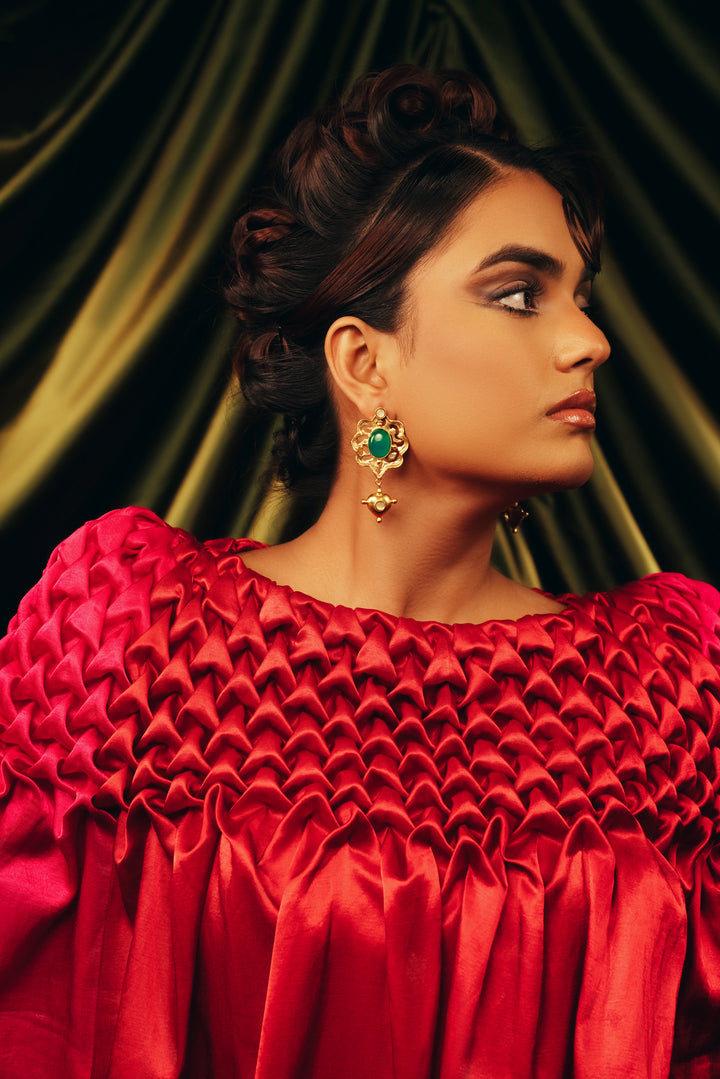 model wearing anti-tarnish gold drop earrings with a rich green central stone and intricate filigree detail.