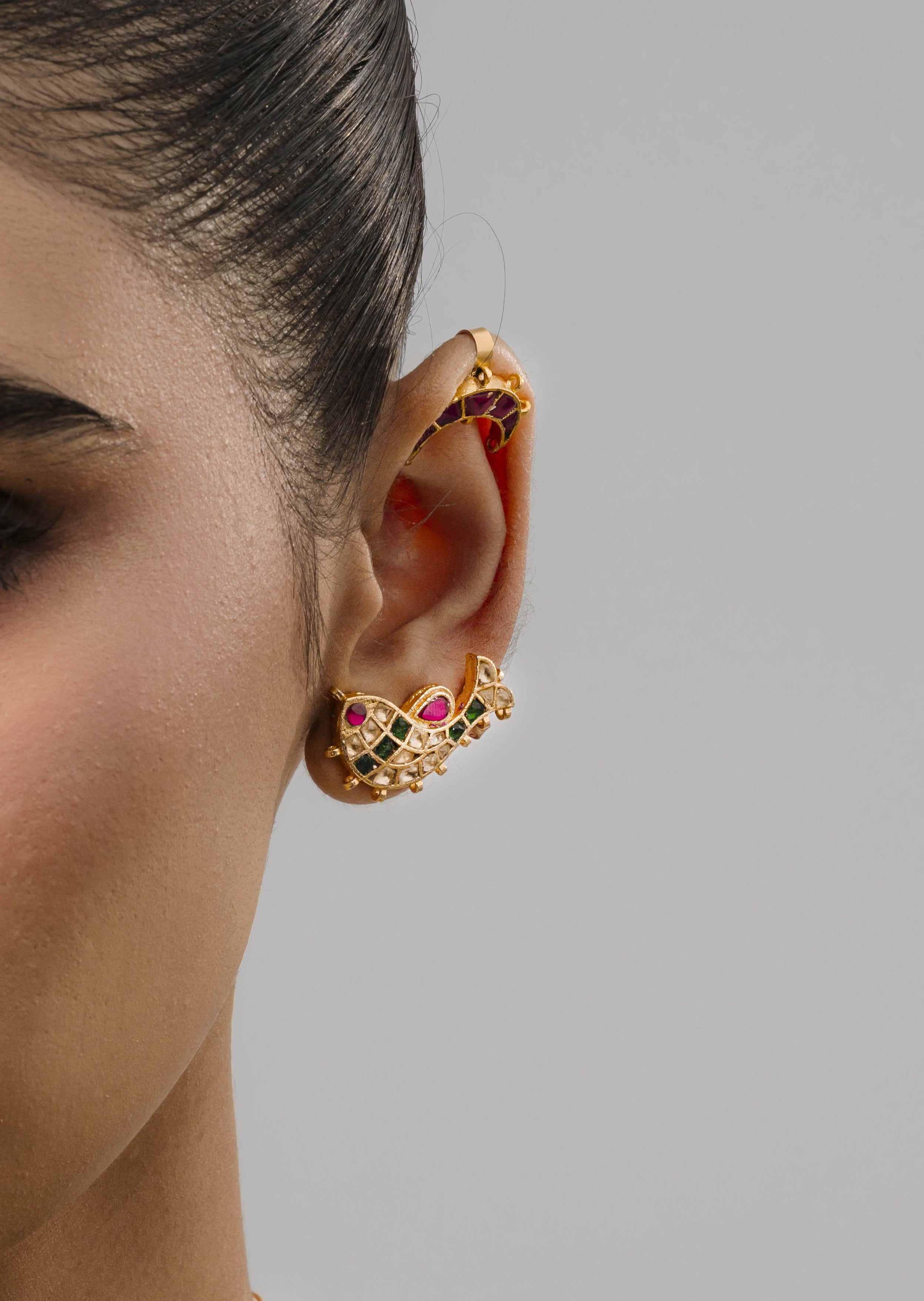 Traditional Indian bridal styling featuring a detailed goldfish ear cuff, multi-coloured gemstone necklace, and a green blouse.