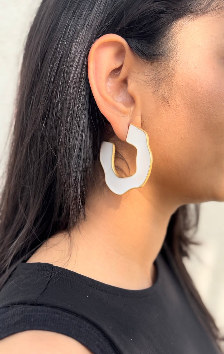 Baalajewels white wave hoop earrings paired with a black top for casual beachwear styling.