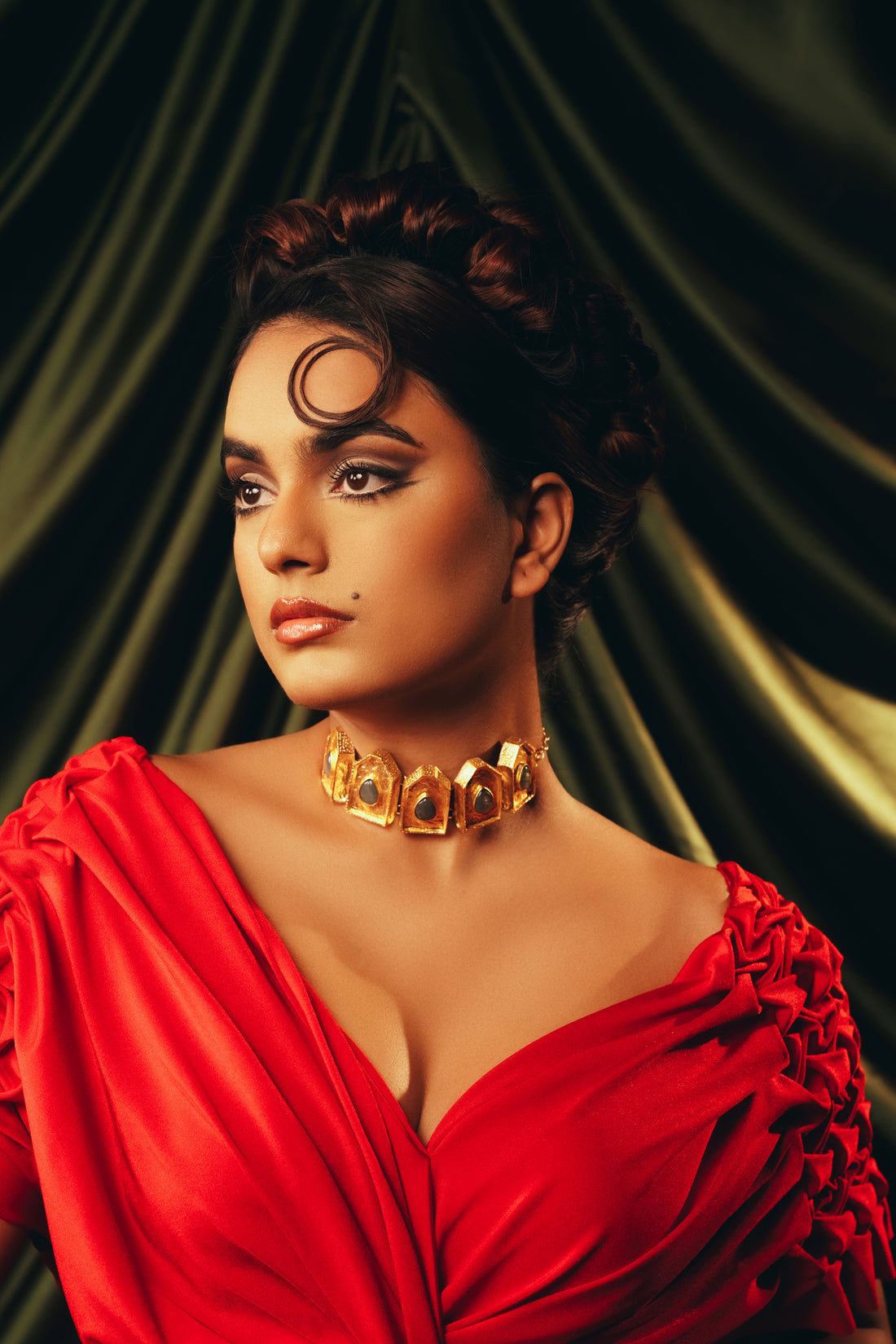 Woman wearing a chunky gold choker necklace with black stone accents for a modern festive look.
