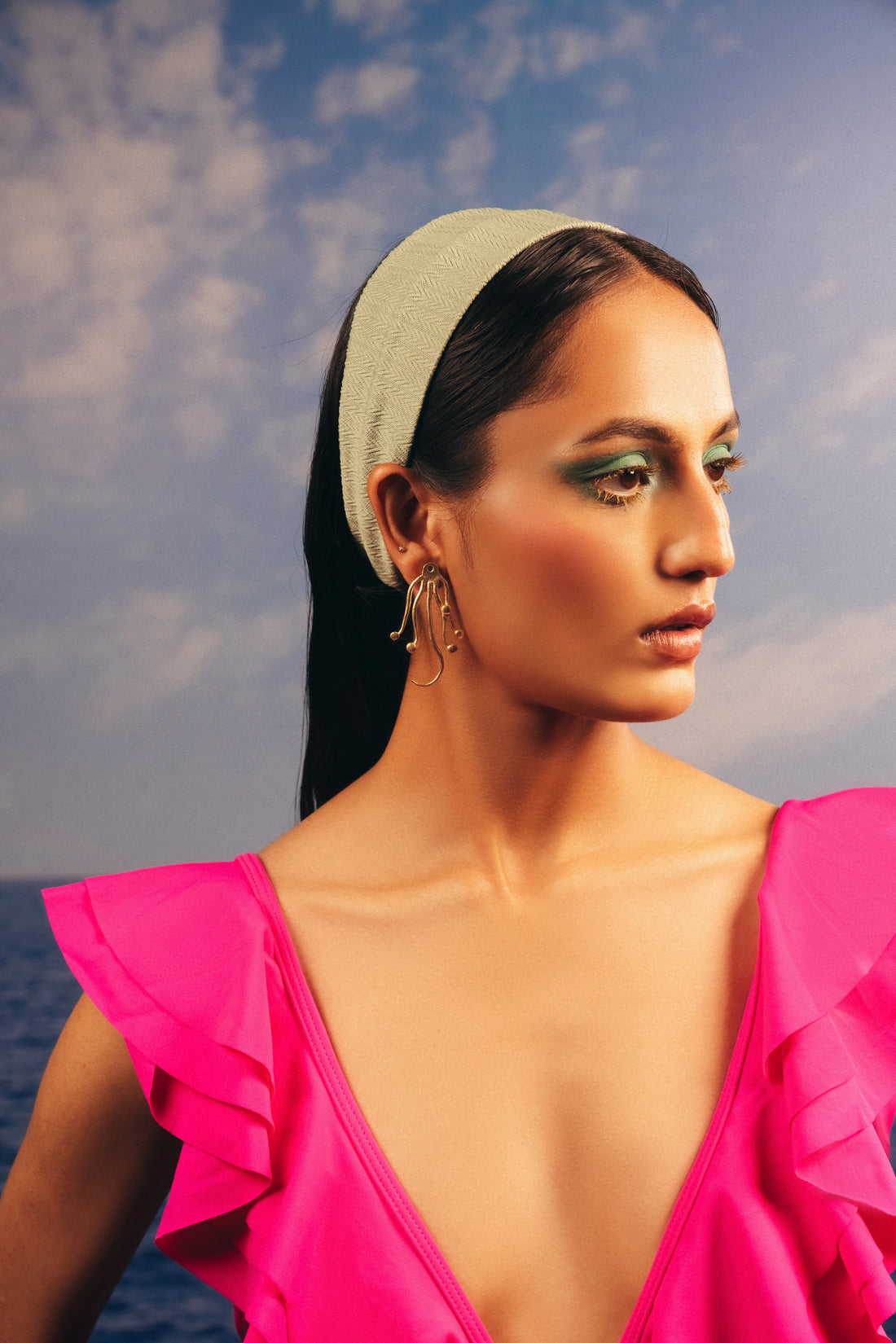 Chunky gold octopus earrings paired with layered jewellery for a bold beach look
