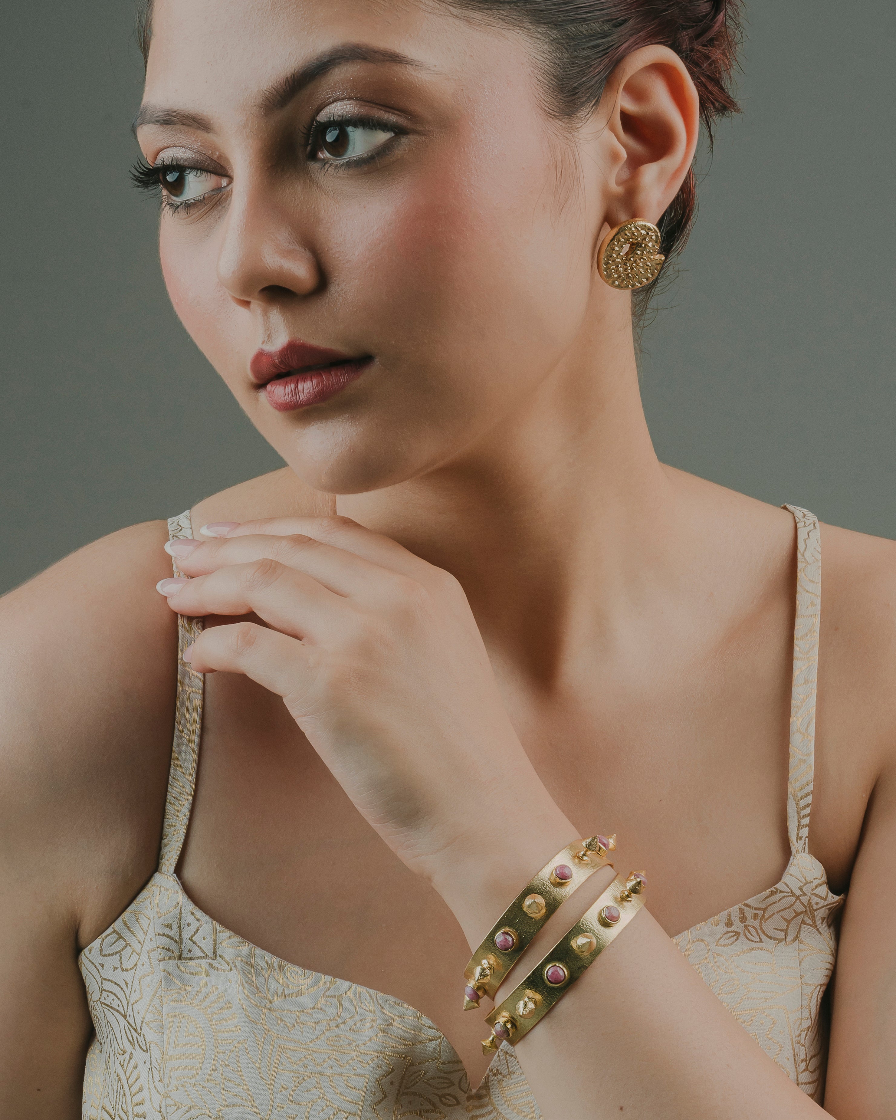 woman wearing statement round gold-toned brass stud earrings for formal or beachwear styling.