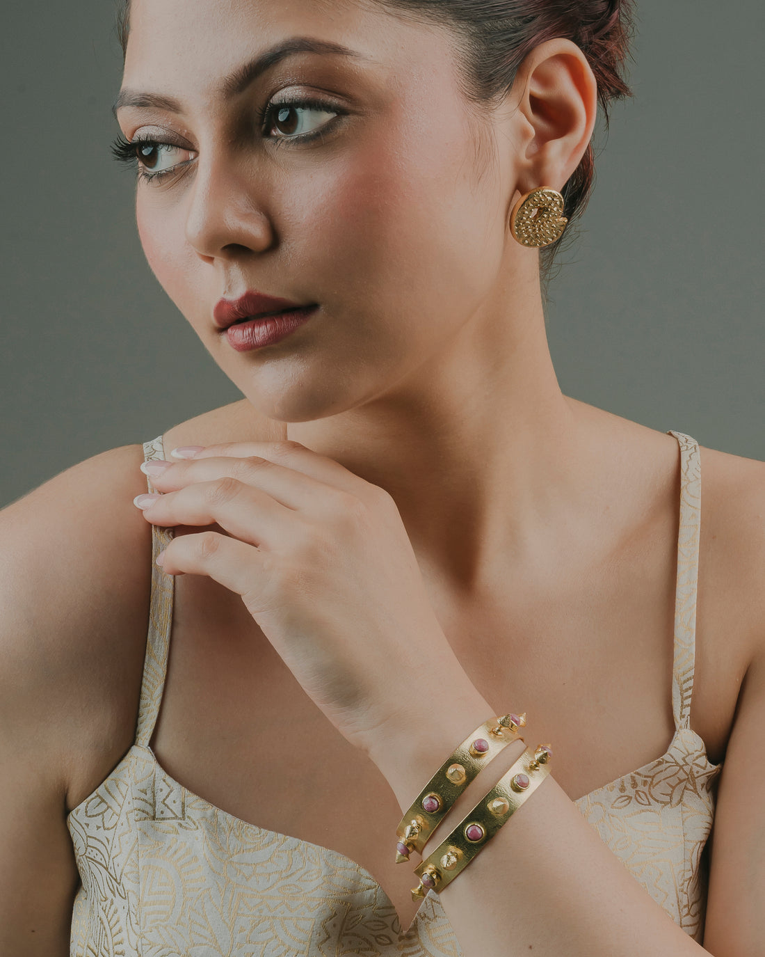 woman wearing statement round gold-toned brass stud earrings for formal or beachwear styling.