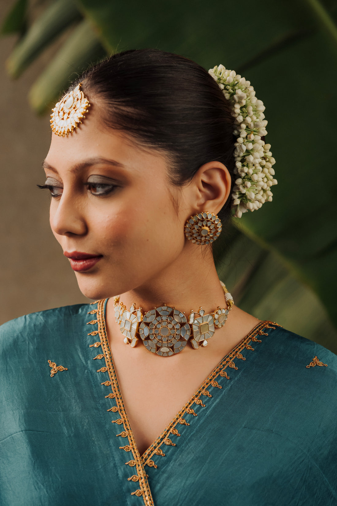Woman wearing Genda Phool traditional Mother of Pearl choker necklace set with stud earrings and blue saree.