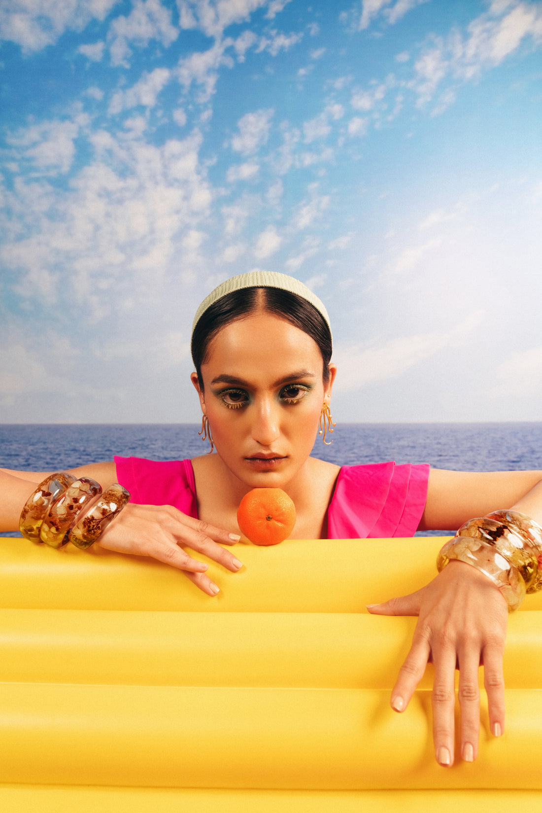 Model wearing gold octopus statement earrings and chunky bracelets for a summer beach look.