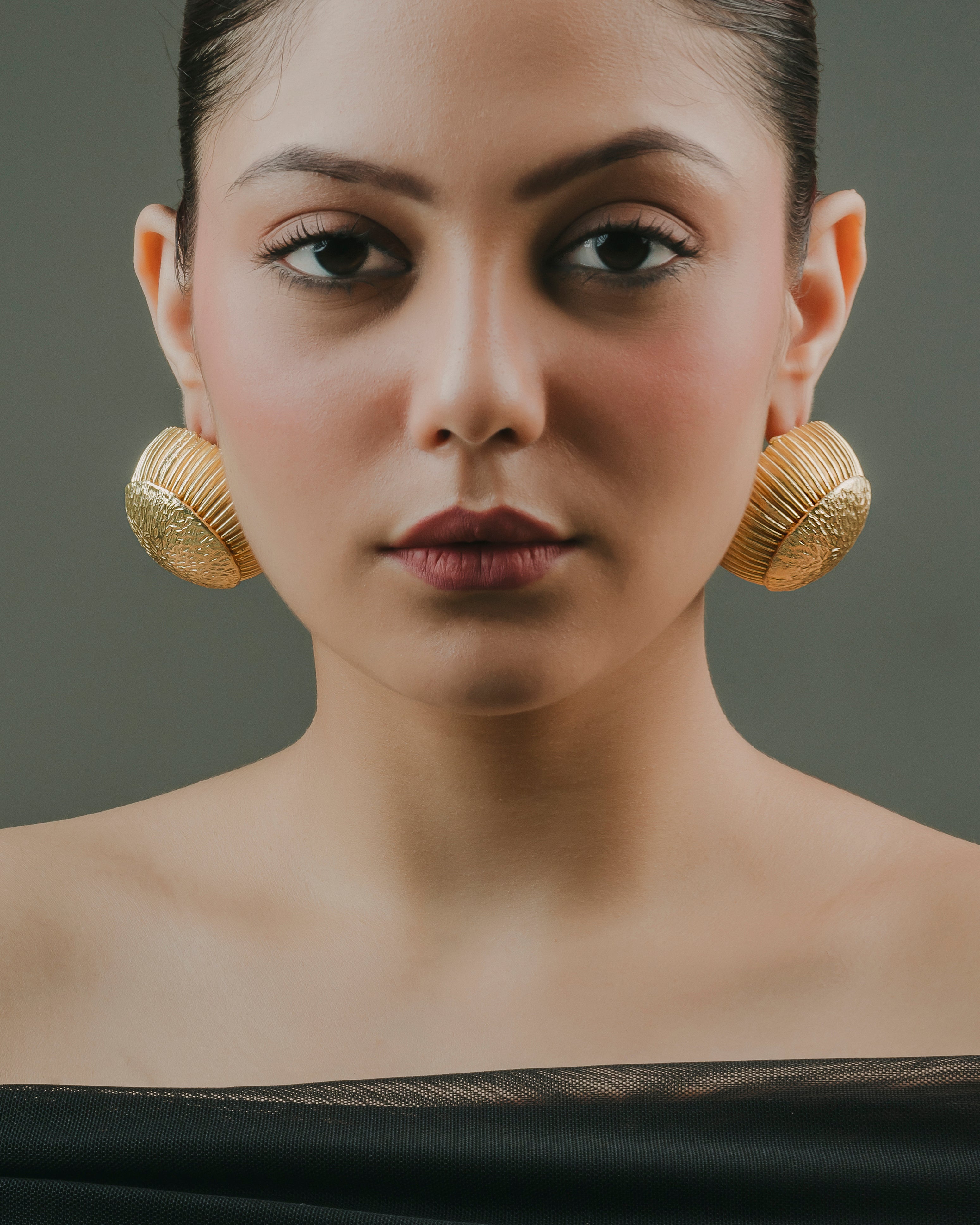 Woman wearing large gold-plated textured hoop earrings with a statement textured finish for summer and evening outfits.