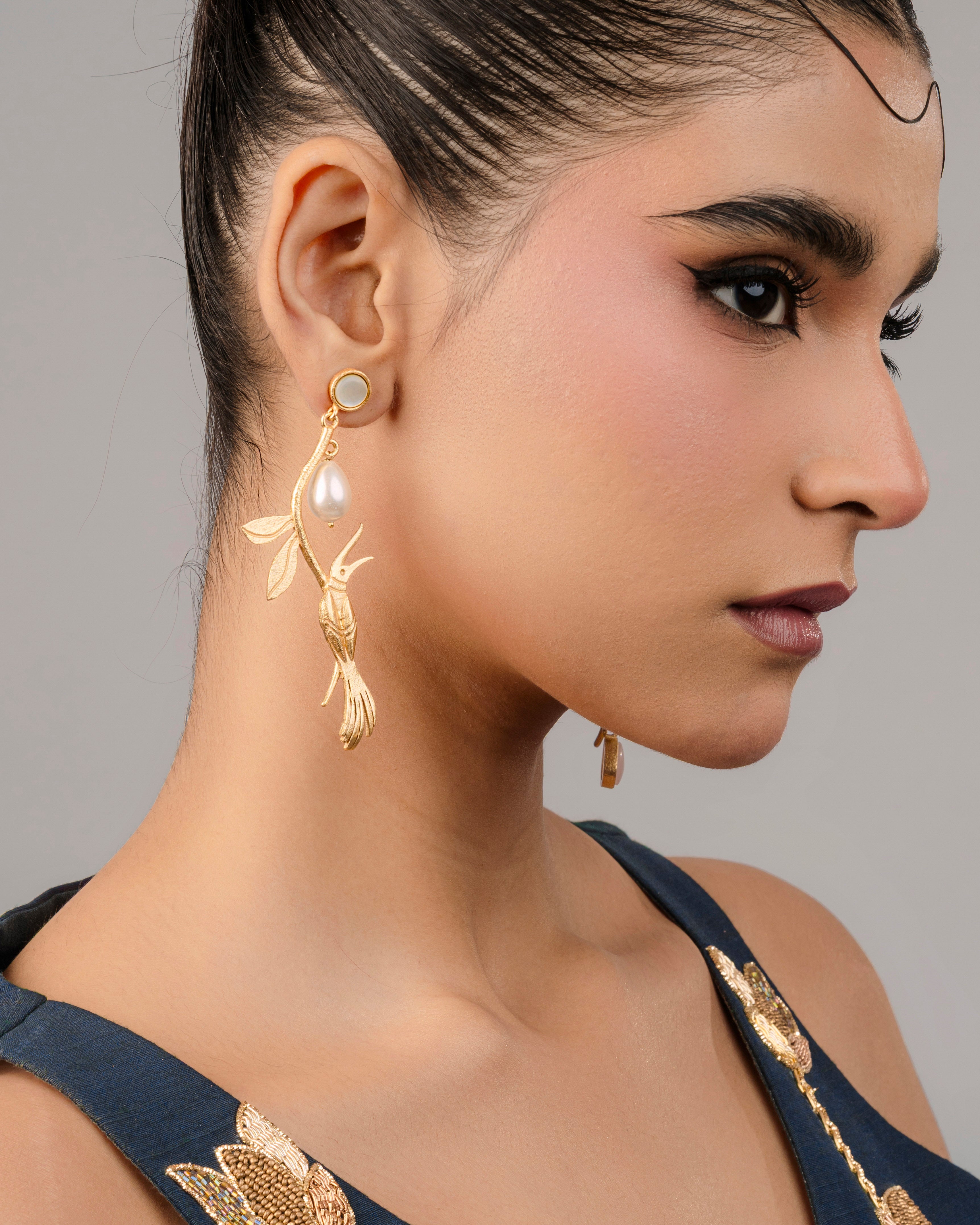 Handcrafted gold-plated fish dangle earrings featuring shimmering pearl accents.