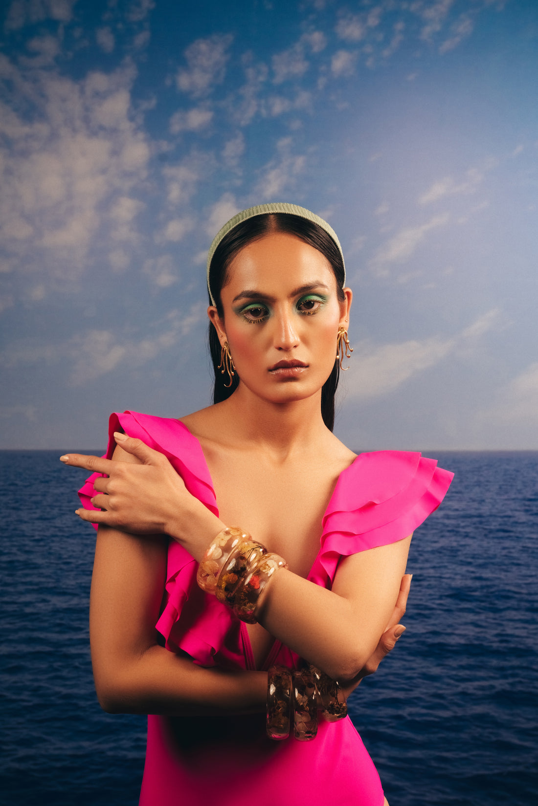 Woman posing by the ocean wearing gold-toned octopus earrings and vibrant beachwear