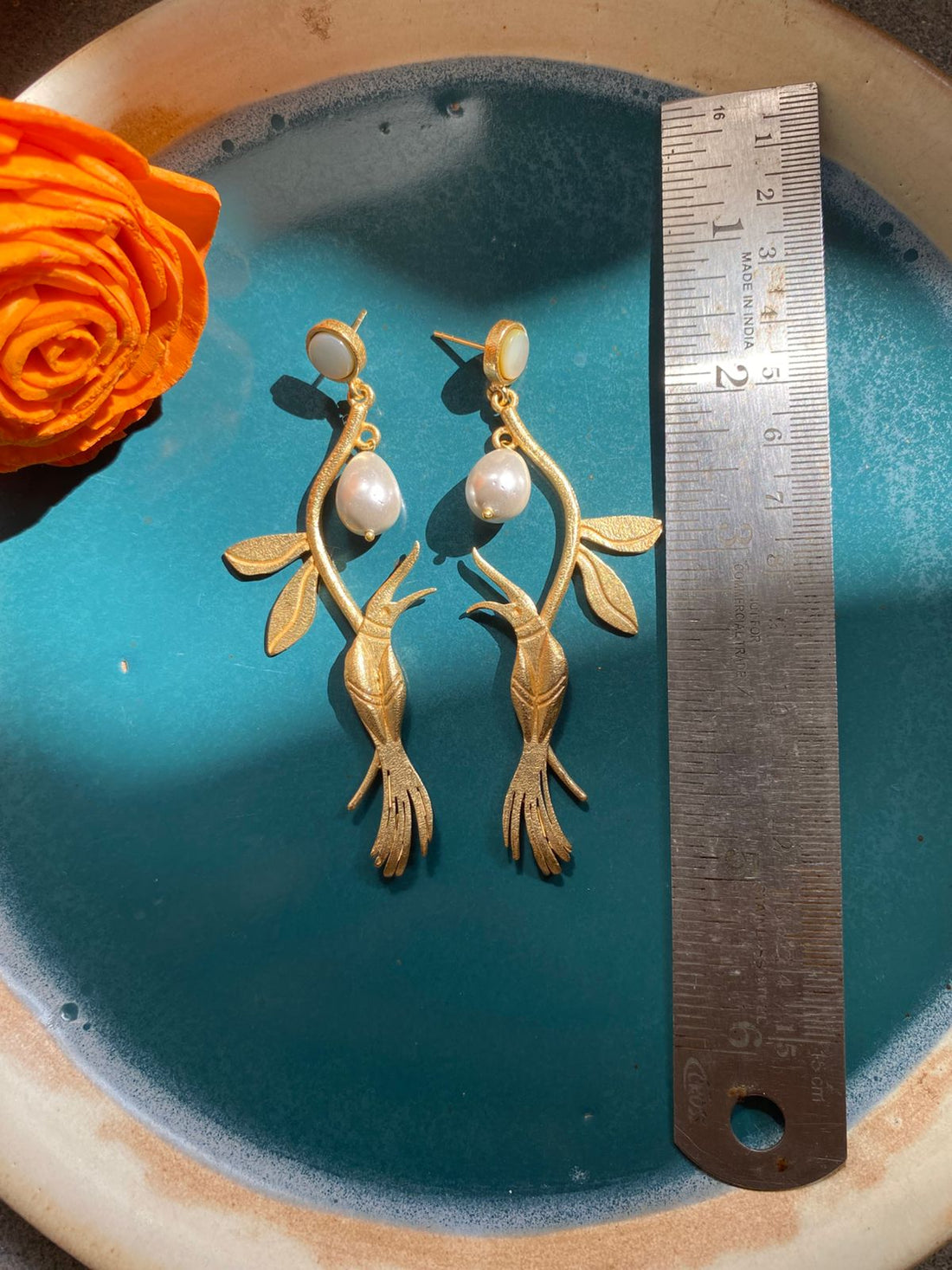 air of elegant gold-plated fish-shaped statement earrings with teardrop pearls.