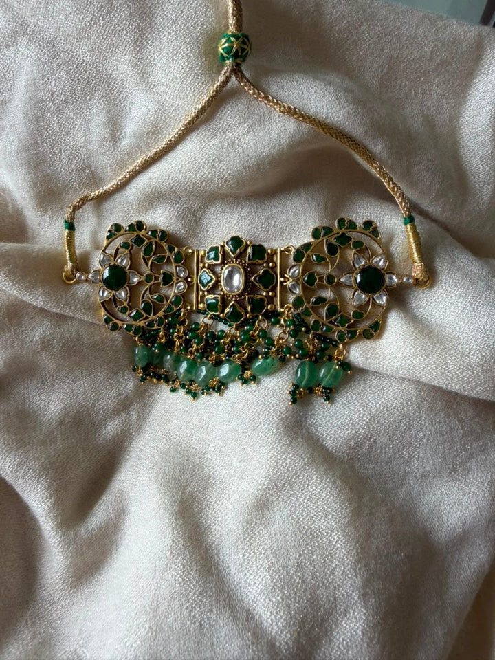 Traditional gold-plated green Kundan choker necklace featuring pearl beaded border and gemstone drops.