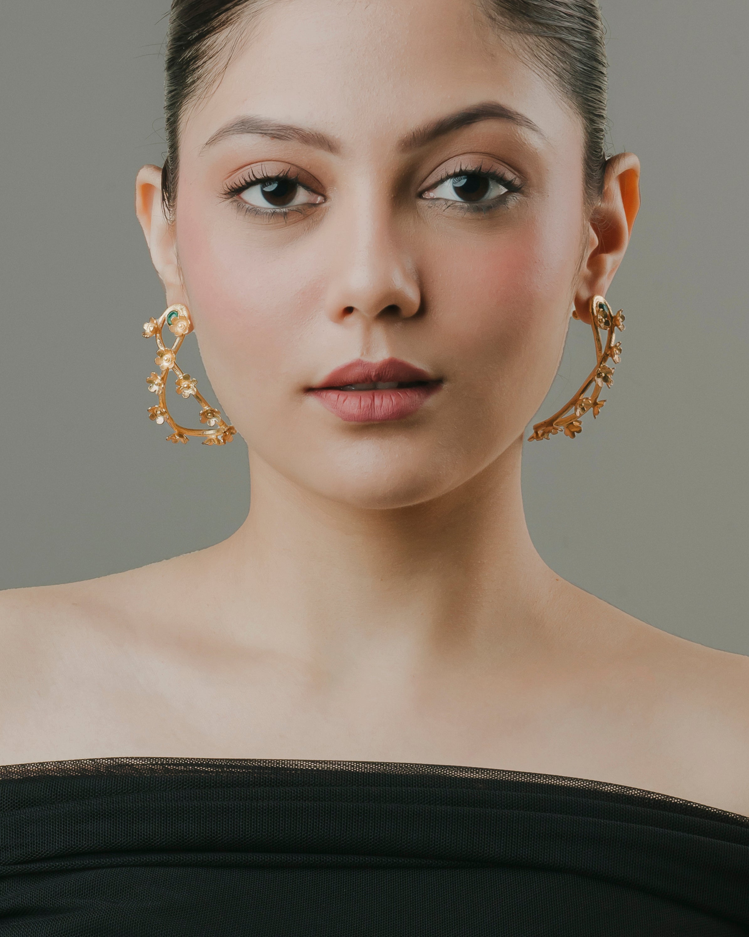 Handcrafted gold-plated open hoop drop earrings with detailed flower motifs and green accent