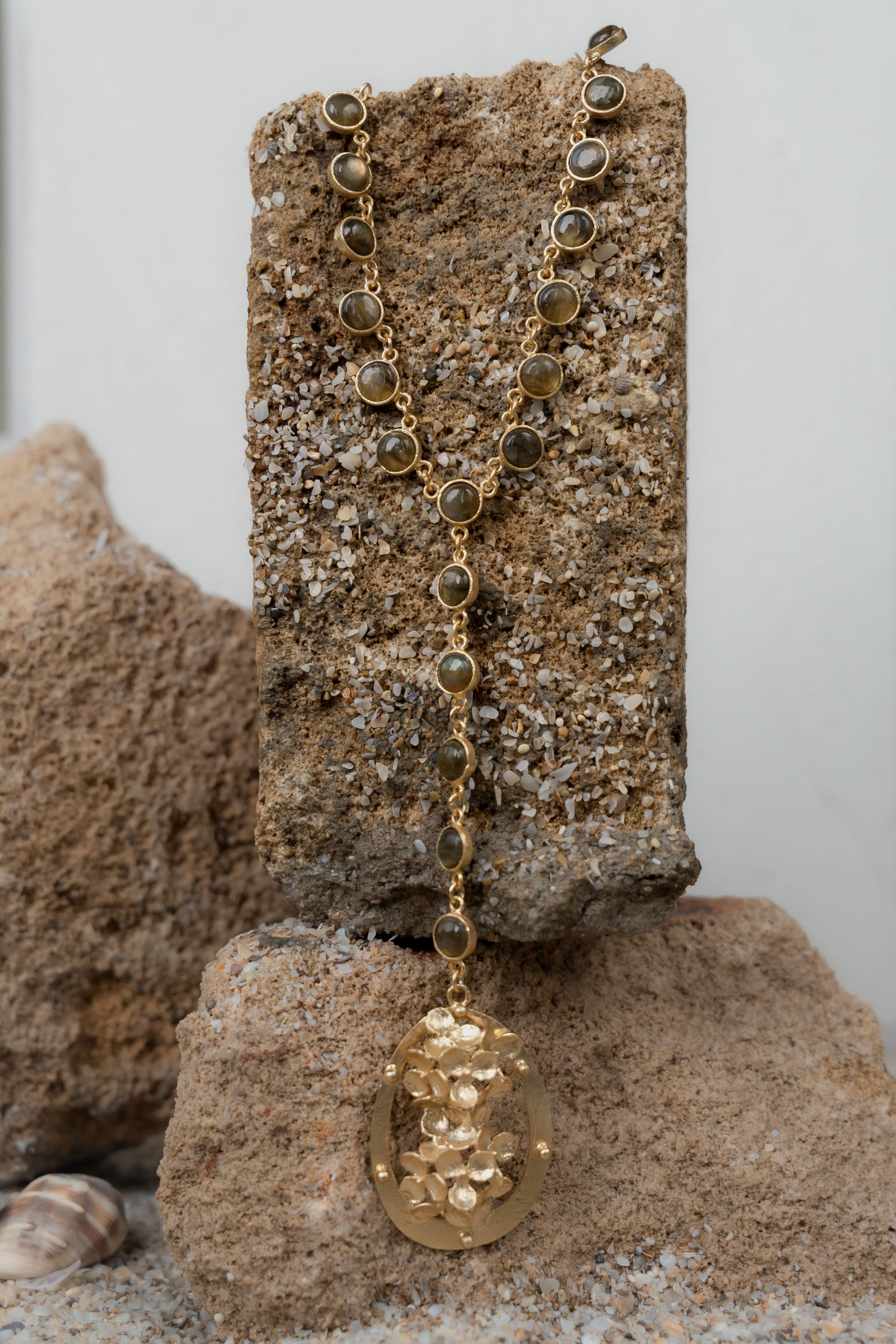 Detailed view of a handcrafted 18k gold-toned statement necklace featuring a floral pendant drop.