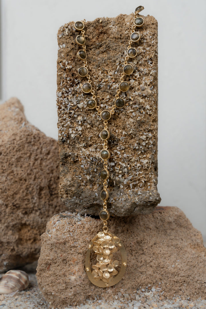 Detailed view of a handcrafted 18k gold-toned statement necklace featuring a floral pendant drop.